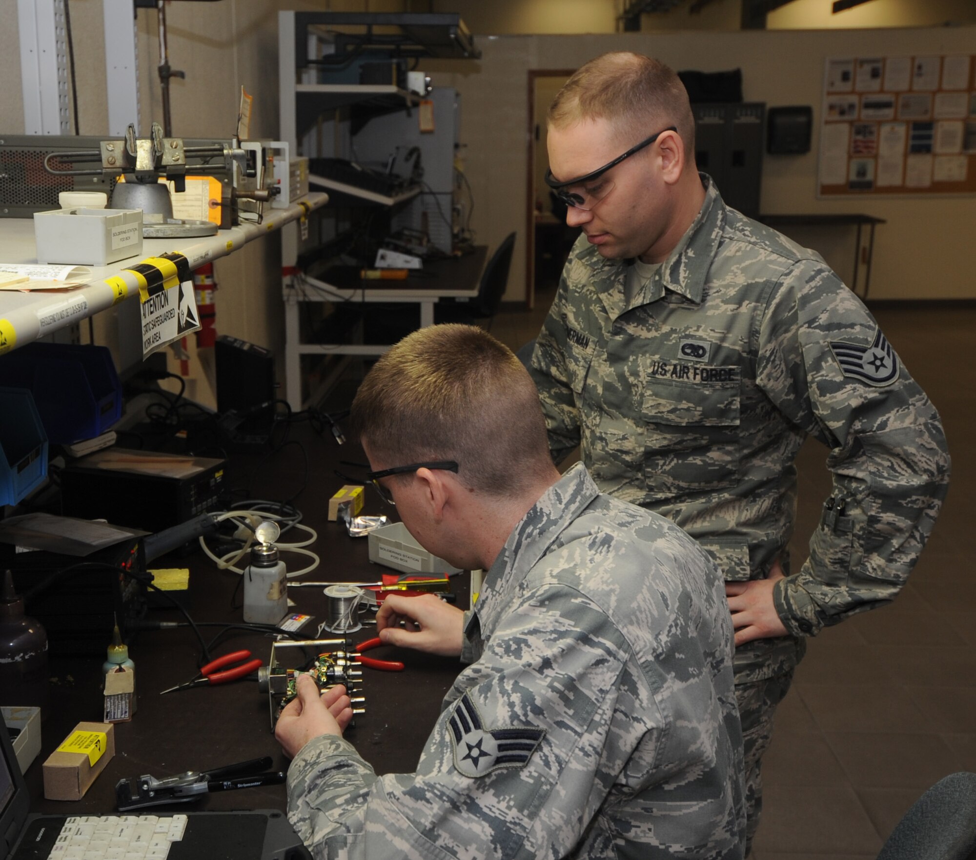 Senior Airman Kevin Burns and Staff Sgt. Eric Zimmerman, 56th Component Maintenance Squadron Avionics Flight team leaders, work on removing a communication switch from an audio panel at the avionics flight. (U.S. Air Force photo by Staff Sgt. Luther Mitchell)