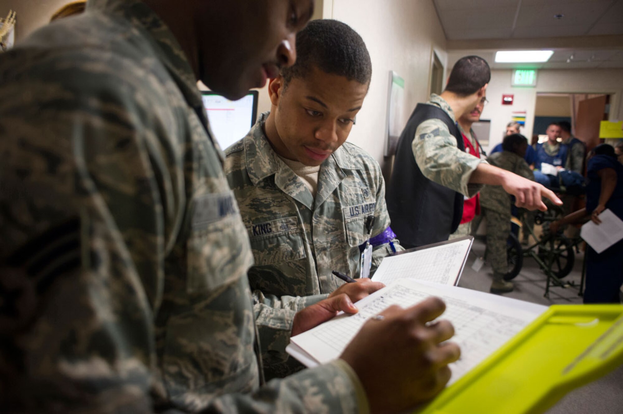 JOINT BASE ELMENDORF–RICHARDSON, Alaska--Senior Airman Broderick Maxie, left, and Airman 1st Class John King, 673d Medical Group, discuss processing emergency patients as a simulated earthquake casualty is rushed down a base hospital hallway at Joint Base Elmendorf-Richardson, Alaska, March 27, 2014, during JBER's Mission Assurance Exercise 14-3. MAE 14-3 is a JBER exercise testing the base’s ability to survive, operate and coordinate during a major natural disaster. (U.S. Air Force photo/Justin Connaher)