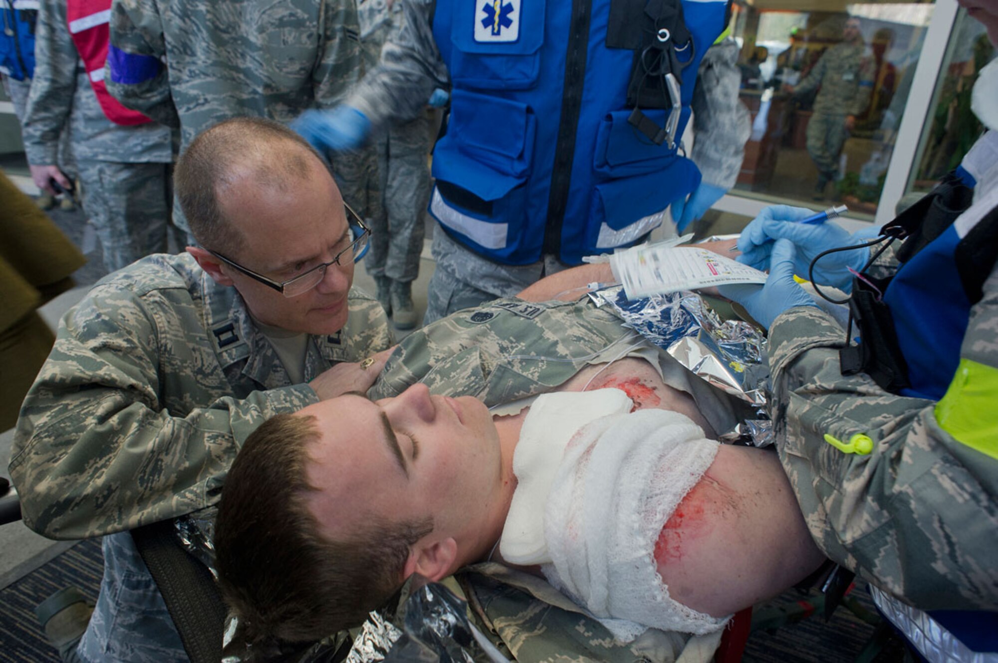 JOINT BASE ELMENDORF–RICHARDSON, Alaska--Air Force Capt. (Chaplain) James Hendricks comforts simulated earthquake casualty Senior Airman Taylor Brown, 673d Communications Squadron, as Airmen from the 673d Medical Group perform triage on him at Joint Base Elmendorf-Richardson, Alaska, March 27, 2014, during JBER's Mission Assurance Exercise 14-3. MAE 14-3 is a JBER exercise testing the base’s ability to survive, operate and coordinate during a major natural disaster.   (U.S. Air Force photo/Justin Connaher)
