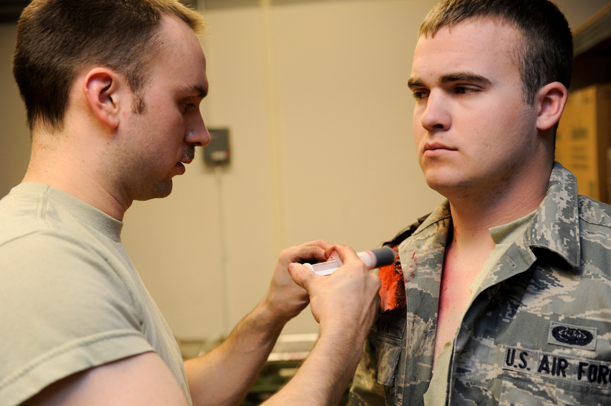 Air Force Staff Sgt. Jonathan Bortz, 673d Dental Squadron dental technician, applies fake blood to Senior Airman Taylor Brown, 673d  Communications Squadron radio frequency transmissions technician, in the basement of a Joint Base Elmendorf-Richardson, building, March 27, 2014. Bortz mission in Mission Assurance Exercise 14-3 is to apply realistic wounds for JBER first responders to practice rapid response in a natural disaster. (U.S. Air Force photo/Senior Airman Omari Bernard)