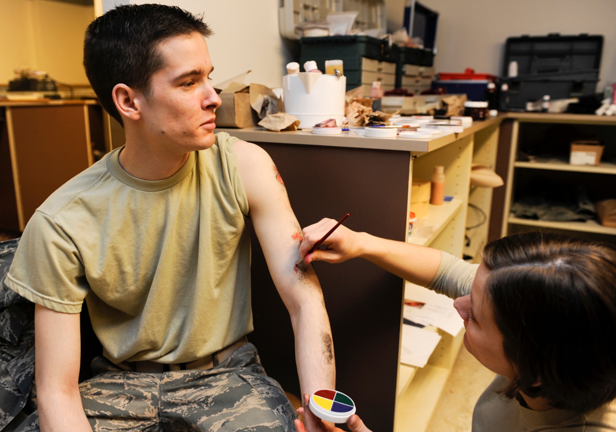 Air Force Staff. Sgt. Jennifer Hurley, 673d Dental Squadron dental technician, applies a moulaged arm wounds to Airman 1st Class Corey Williams, 3rd Operations Support Squadron air traffic controller, in preparation for Mission Assurance Exercise 14-3 March 27, 2014 on Joint Base Elmendorf-Richardson, Alaska. MAE 14-3 is one of many exercises that fall under exercise Alaska Shield. (U.S. Air Force photo Senior Airman Omari Bernard)