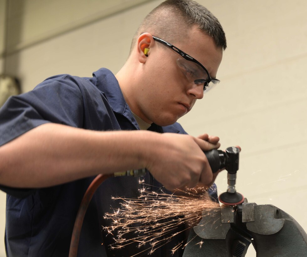 Senior Airman Justin Morris, 28th Maintenance Squadron metals technician, uses a hand grinder to trim an egress seat spacer in the Metals Shop at Ellsworth Air Force Base, S.D., March 25, 2014. Metals technology technicians are certified in welding specifications, metal tempering, forging, mechanical drawings and the use of precision measuring devices. (U.S. Air Force photo by Airman 1st Class Rebecca Imwalle/Released)