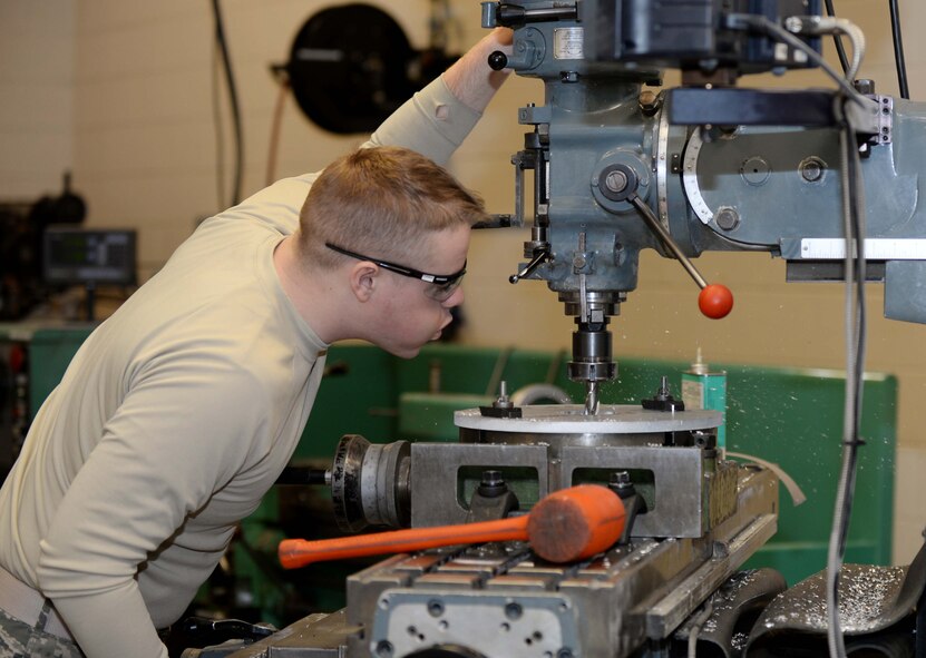 Airman 1st Class Drake Anderson, 28th Maintenance Squadron metals technician, blows metal shavings off a drill press plate in the Metals Shop at Ellsworth Air Force Base, S.D., March 25, 2014. Metals technology technicians are trained to perform a variety of metal manufacturing and repairs to ensure equipment remains serviceable. (U.S. Air Force photo by Airman 1st Class Rebecca Imwalle/Released) 