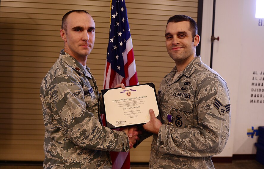 U.S. Air Force Senior Airman Michael Haffner, 822d Base Defense Squadron fire team member (right), receives a Purple Heart Medal certificate from Maj. Christopher Hagemeyer, 822d BDS commander, at Moody Air Force Base, Ga., March 27, 2014. During a security patrol while deployed to Bagram Airfield, Afghanistan, Haffner’s truck hit an improvised explosive device. As a result, Haffner sustained a traumatic brain injury and permanently lost 70 percent of his hearing. (U.S. Air Force photo by Senior Airman Tiffany M. Grigg/Released) 