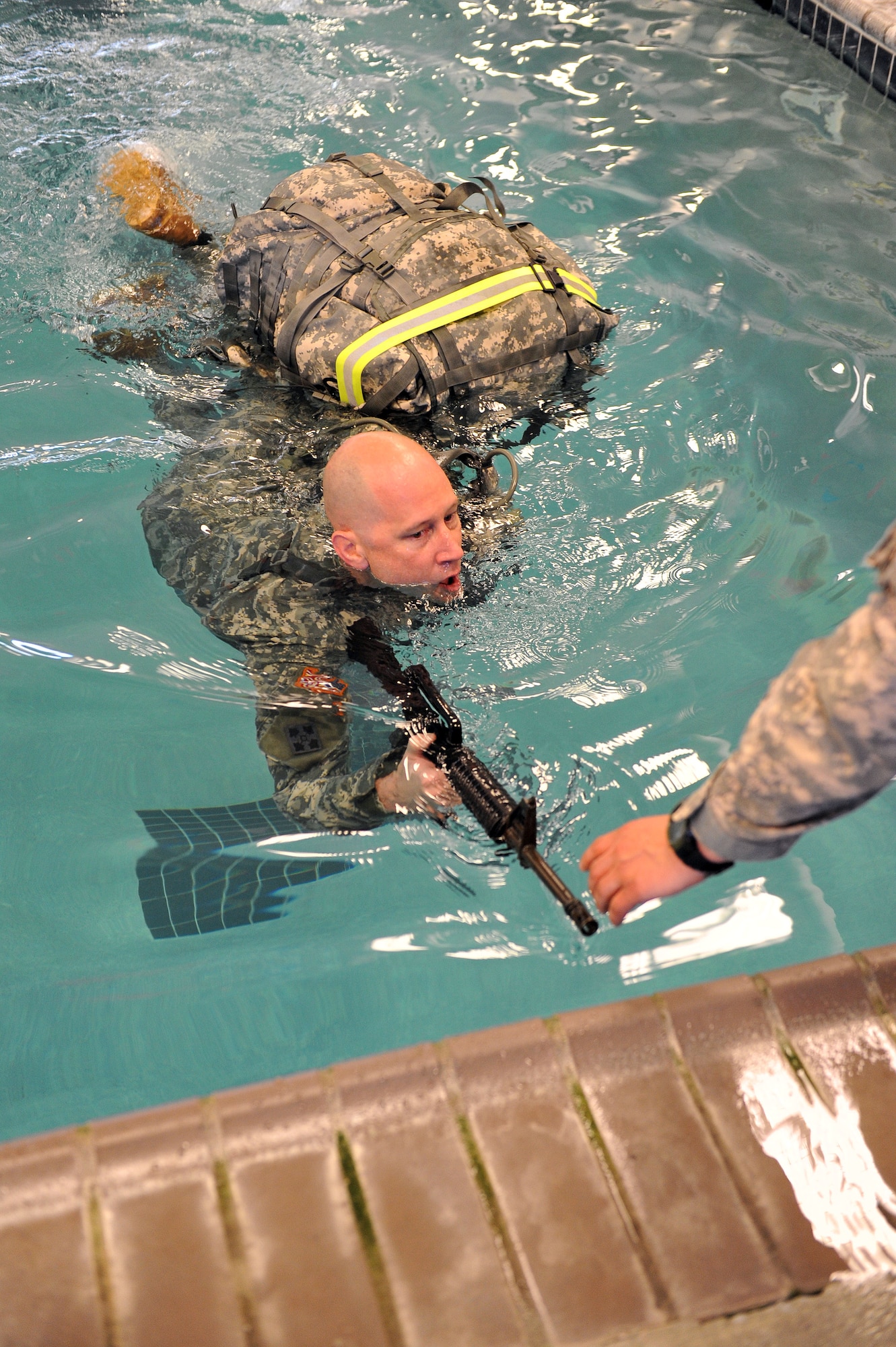 Maj. Will Vogan, Deputy Mission Crew commander, swims with a rubber M-4 firearm and a rucksack during water survival training. (U.S. Air Force photo by Tommie Horton)