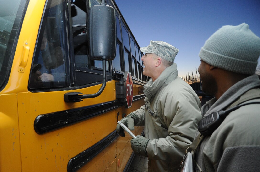 Col. Paul Bauman (center), 319th Air Base Wing commander, greets a school bus entering Grand Forks Air Force Base, N.D., March 28, 2014. Bauman and 319th ABW Command Chief Master Sgt. David Duncan spent the morning at the main gate checking ID cards and greeting drivers and pedestrians. (U.S. Air Force photo/Staff Sgt. David Dobrydney)