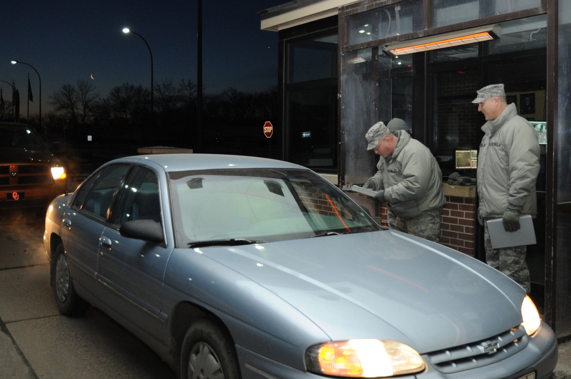 Col. Paul Bauman (right), 319th Air Base Wing commander, and 319th ABW Command Chief Master Sgt. David Duncan check ID cards of people arriving on Grand Forks Air Force Base, N.D., March 28, 2014. Wing leadership spent an hour greeting drivers and assisting Airmen from the 319th Security Forces Squadron during the morning rush. (U.S. Air Force photo/Staff Sgt. David Dobrydney)