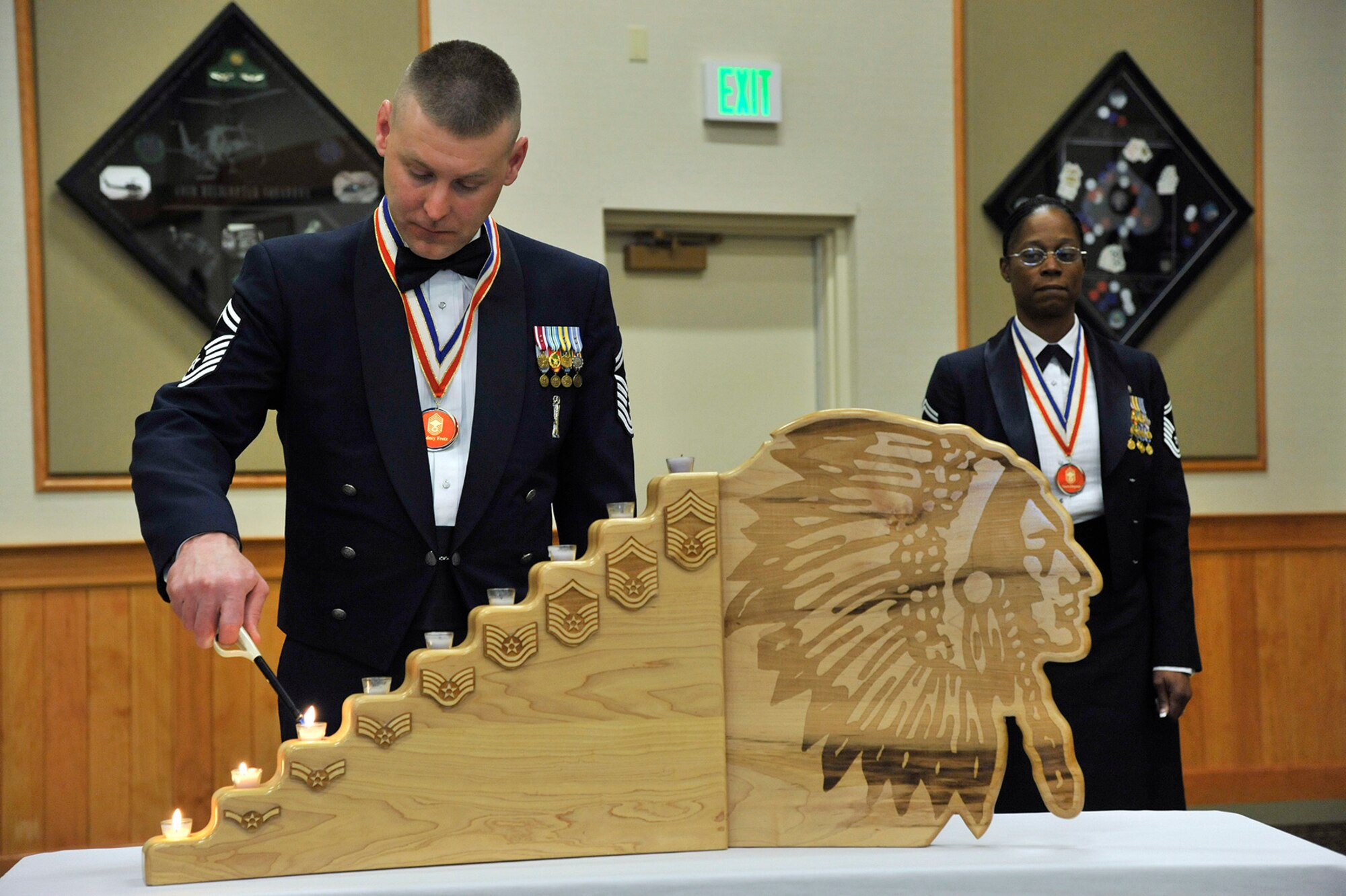 Senior Master Sgt. Rodney Frotz, 341st Missile Maintenance Squadron superintendent, lights the first few candles during the candle lighting ceremony as part of the Chief Recognition Banquet at the Grizzly Bend on March 21. Senior Master Sgt. Nanette Klingaman, 341st Security Forces Squadron superintendent, looks on. (U.S. Air Force photo/John Turner)