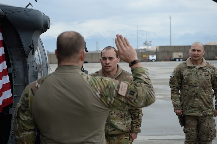 Senior Master Sgt. Carmelo Vega Martinez, 438th Air Expeditionary Wing/NATO Air Training Command-Afghanistan recruiting adviser, watches as U.S. Air Force Capt. Adam Gram, 83rd Expeditionary Rescue Squadron pilot administers the oath of enlistment to his son Staff Sgt. Jean Vega Martinez, 83rd ERQS flight engineer, during a reenlistment ceremony March 17 at Bagram Air Field, Afghanistan. Prior to the ceremony, father and son, both Ponce, Puerto Rico natives, hadn't seen each other in two years due to military commitments. The two are deployed at separate Operation Enduring Freedom bases, 40 miles across the combat zone. Senior Master Sgt. Vega Martinez's home station is Hill Air Force Base, where he's assigned to the 368th Recruiting Squadron.(U.S. Air Force photo by Tech. Sgt. Jason Robertson)
