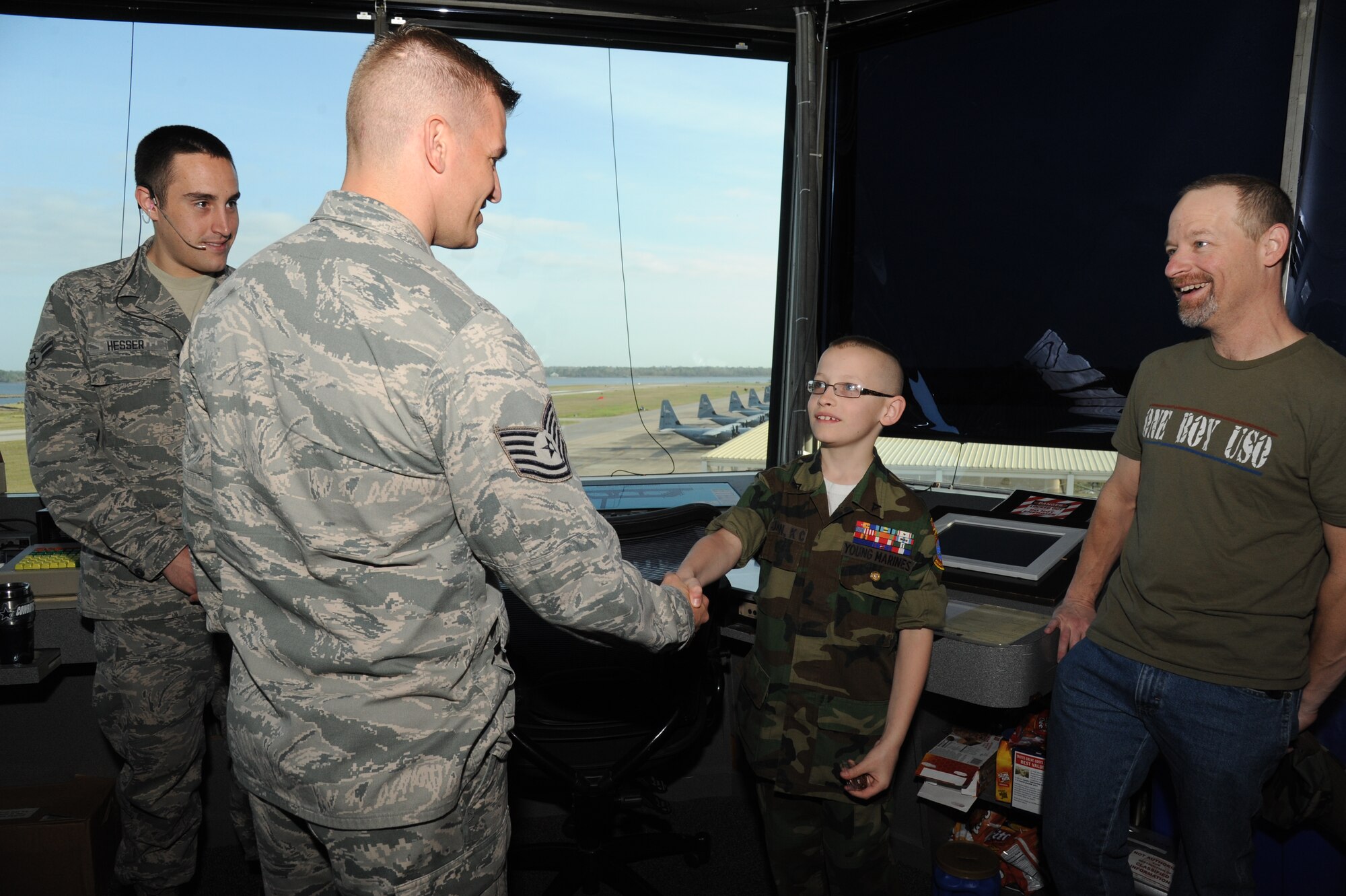Tech. Sgt. David Hough, 81st Operation Support Flight, presents a coin to eleven-year-old Cody Jackson, as Airman 1st Class Daryle Hesser, 334th Training Squadron, and Cody’s dad, stand by during a tour of the air traffic control tower March 27, 2014, Keesler Air Force Base, Miss.  Jackson, from Alpharetta, Ga., is known as "One Boy USO" for his personal mission to thank as many military members as he can, either by shaking hands, welcoming them home or sending packages to deployed troops.  He was accompanied by his parents and staff members from the local chapter of the American Red Cross. (U.S. Air Force photo by Kemberly Groue)