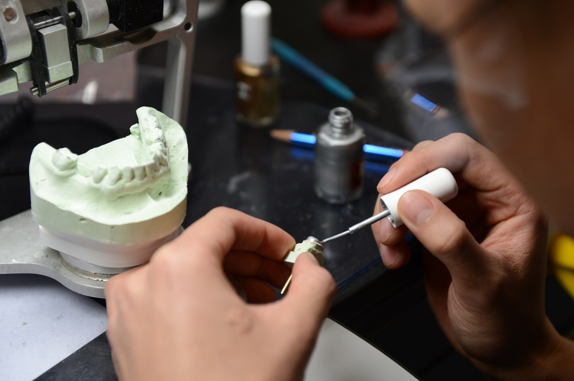 U.S. Air Force Staff Sgt. John Castillo, 52nd Dental Squadron dental laboratory technician from San Diego, paints a stone tooth at Spangdahlem Air Base, Germany, March 28, 2014. After the tooth is prepared, it is used to create a crown made from porcelain fused to metal and is placed over the patients tooth. (U.S. Air Force photo by Airman 1st Class Kyle Gese/Released)