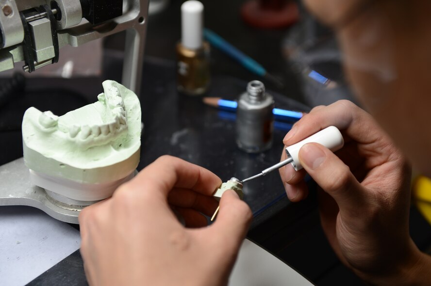 U.S. Air Force Staff Sgt. John Castillo, 52nd Dental Squadron dental laboratory technician from San Diego, paints a stone tooth at Spangdahlem Air Base, Germany, March 28, 2014. After the tooth is prepared, it is used to create a crown made from porcelain fused to metal and is placed over the patients tooth. (U.S. Air Force photo by Airman 1st Class Kyle Gese/Released)