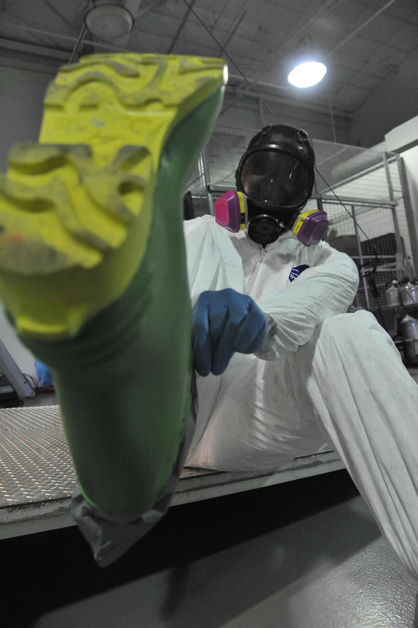 U.S. Air Force Tech. Sgt. Ronnie B. McGee, 509th Medical Operations Squadron bioenviromental technician, puts on a chemical protective boot at Whiteman Air Force Base, Mo., March 13, 2014. This all-purpose boot is used to prevent exposure from chemicals, radiation and sharp objects. (U.S. Air Force photo by Airman 1st Class Keenan Berry/Released)