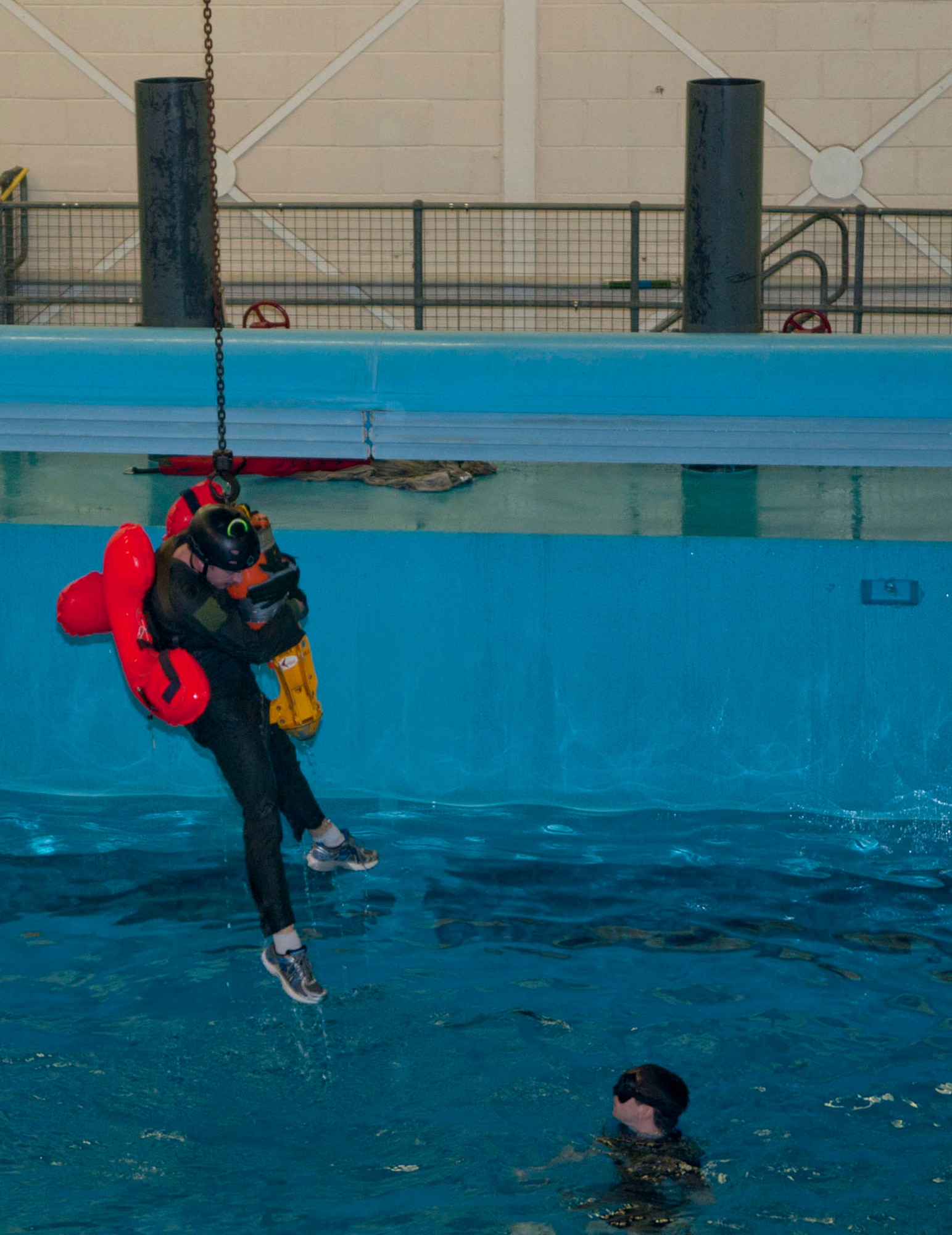 A forest penetrator hoists an RAF Lakenheath aircrew member from the water to simulate a helicopter hoist during water survival training March 20, 2014, at Lowestoft College in Norfolk, England. Survival, Evasion, Resistance and Escape specialists from RAF Mildenhall and RAF Lakenheath taught this life-saving training to aircrew from both bases, to physically familiarize them with the operational use of equipment in less-than-ideal conditions. Part of the exercise included demonstrations of personnel recovery devices such as a helicopter ladder and cargo ladder. (U.S. Air Force photo by Karen Abeyasekere/Released)
