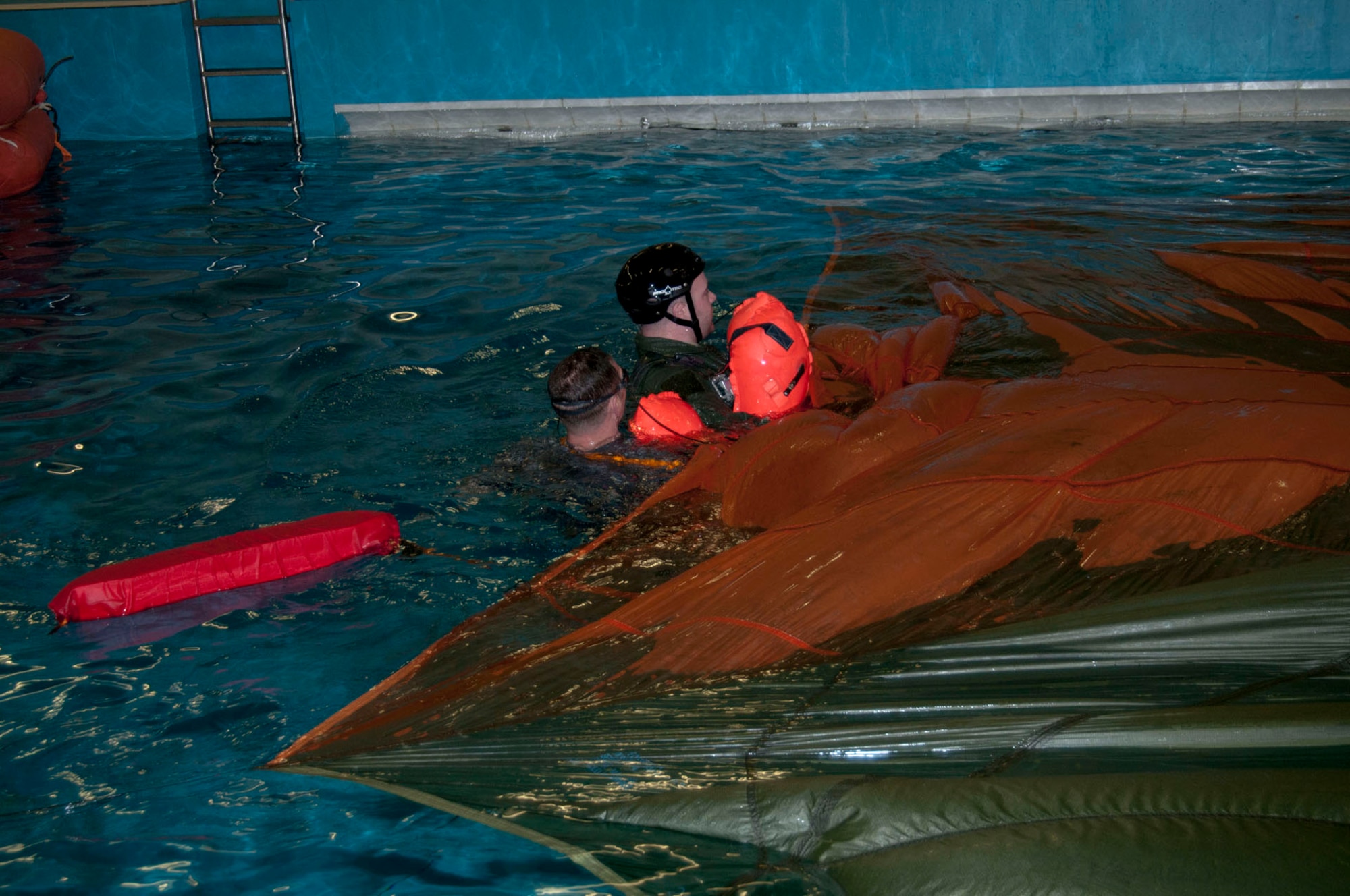 A Survival, Evasion, Resistance and Escape specialist from RAF Mildenhall helps disentangle an aircrew member from a parachute canopy during water survival training March 20, 2014, at Lowestoft College in Norfolk, England.  Canopy disentanglement is one of many scenarios the SERE specialists teach. It simulates a parachute landing on top of an individual, enabling that person to learn the required techniques to get out from under the parachute without becoming entangled in the lines and shroud. (U.S. Air Force photo by Karen Abeyasekere/Released)
