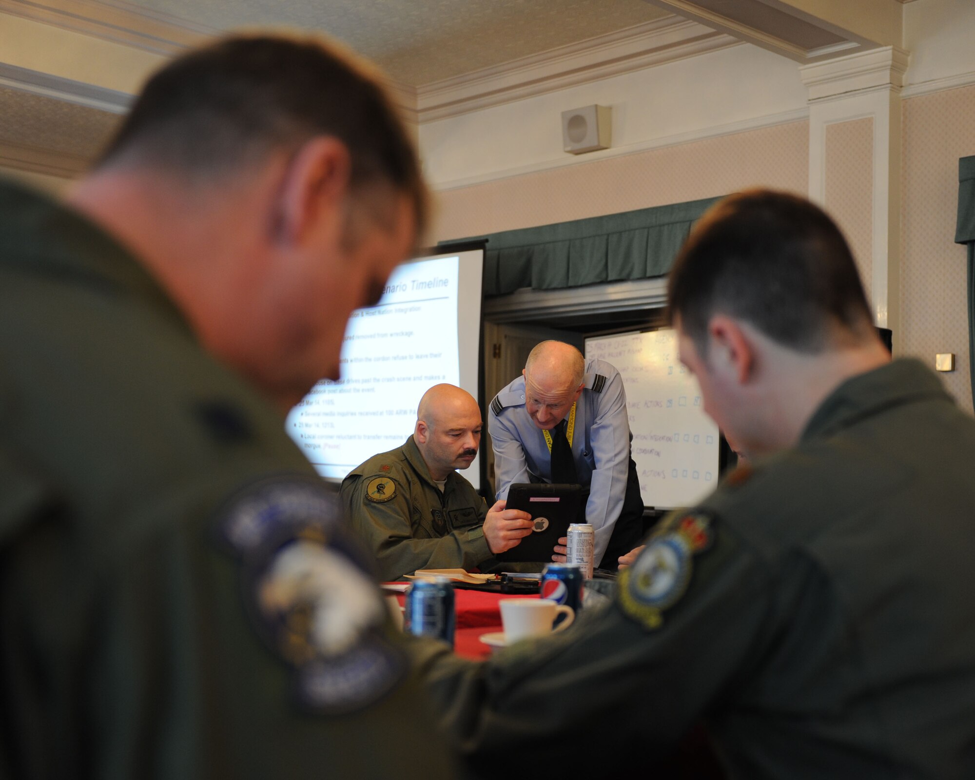U.S. Air Force Maj. Dale Linafelter, back left, 352nd Special Operations Support Squadron assistant director of operations, speaks with Royal Air Force Sqn. Ldr. Rick Fryer, back right, RAF Mildenhall station commander, during a tabletop exercise March 25, 2014, on RAF Mildenhall, England. During a tabletop exercise, representatives from different agencies simulate responses to a mock emergency. This prepares U.S. Air Force units, members of the RAF and local nationals to communicate with one another in the event of a real emergency, without involving as many personnel as a full-scale exercise. (U.S. Air Force photo by Airman 1st Class Preston Webb/Released)