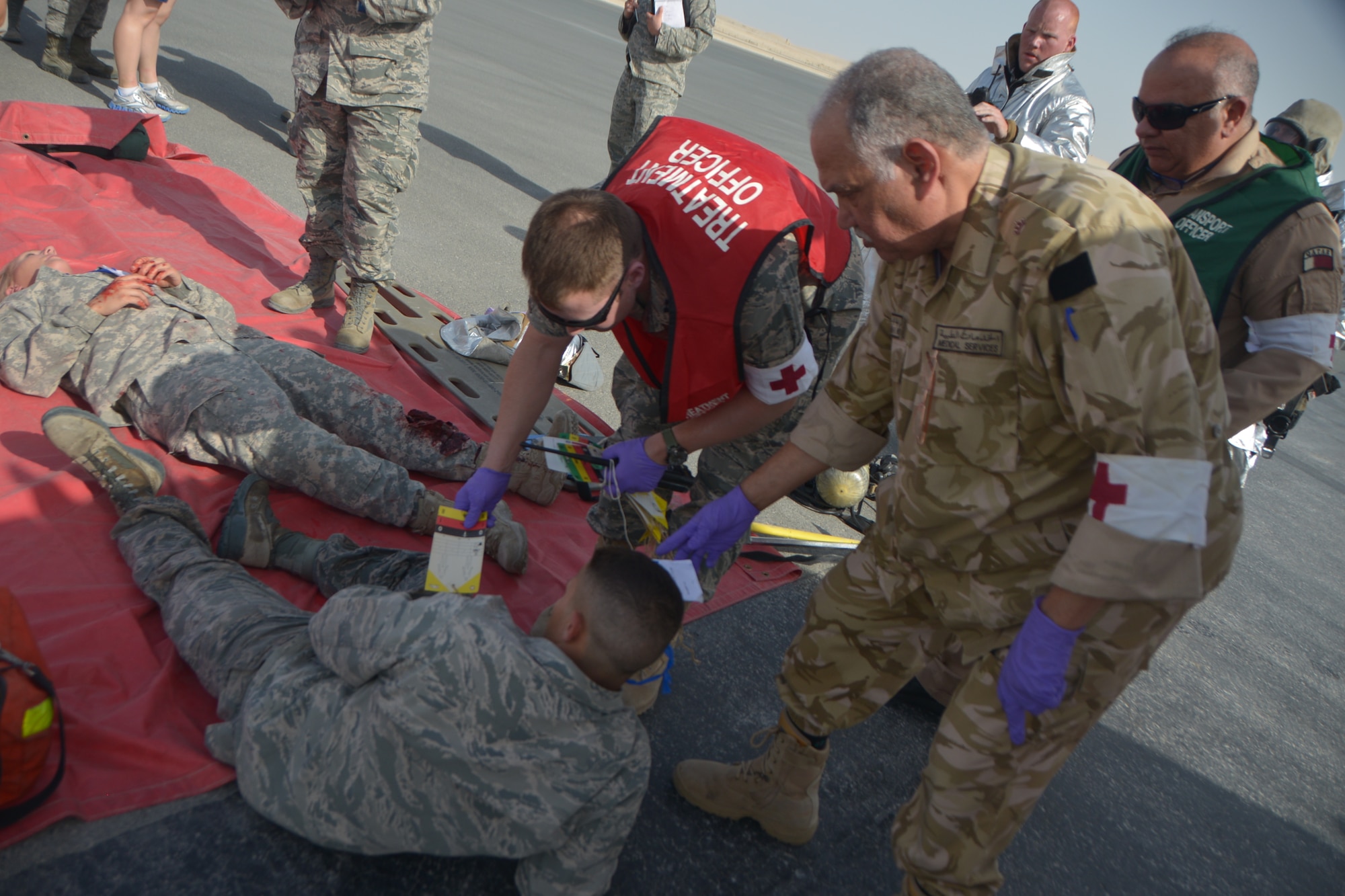 Air Force and Qatar Emiri Air Force first responders classify injuries of simulated patients during a base-wide Major Accident Response Exercise at Al Udeid Air Base, Qatar, March 21, 2014. The simulated scenario for the MARE involved a C-130 Hercules which crashed at the end of a runway with 20 service members onboard. Organizations from all over the base including host nation counterparts had to react to the exercise as if it were the real deal. (U.S. Air Force photo/Senior Airman Jared Trimarchi) 