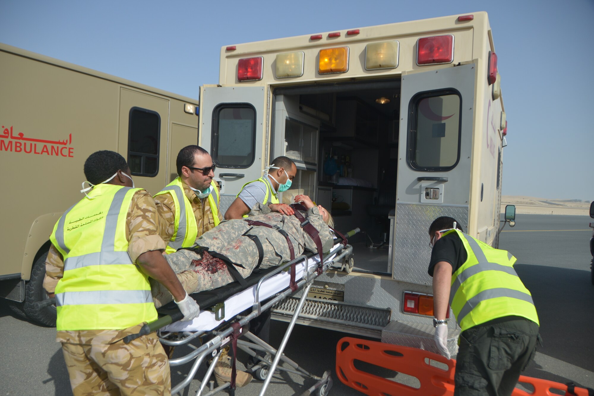 Qatar Emiri Air Force first responders prepare to transport a simulated patient onto an ambulance during a base-wide Major Accident Response Exercise at Al Udeid Air Base, Qatar, March 21, 2014. The simulated scenario for the MARE involved a C-130 Hercules which crashed at the end of a runway with 20 service members onboard. Organizations from all over the base including host nation counterparts had to react to the exercise as if it were the real deal. (U.S. Air Force photo/Senior Airman Jared Trimarchi) 