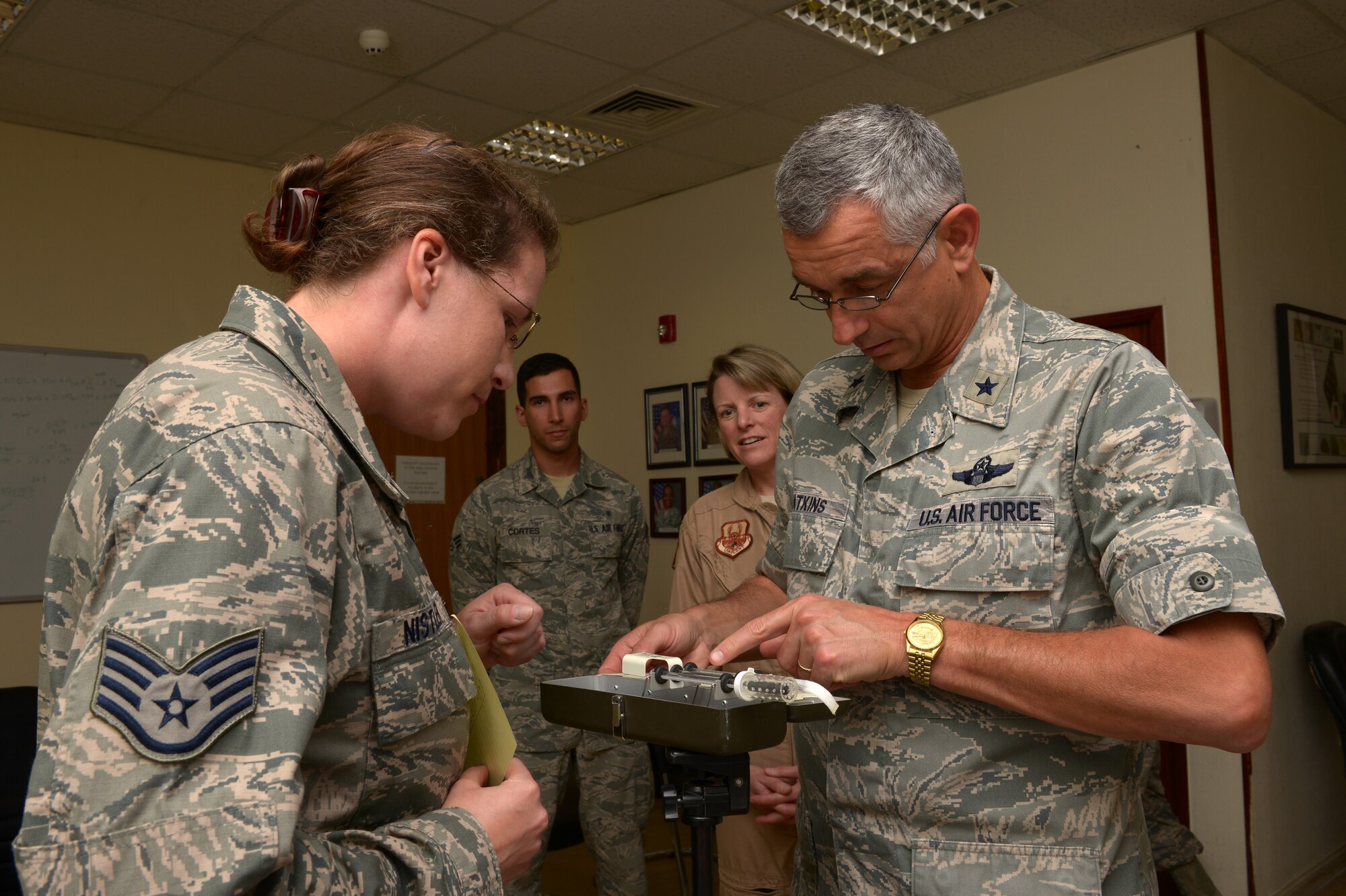 Staff Sgt. Stefani Nistler briefs Brig. Gen. Roger H. Watkins on a wet bulb globe thermometer at Al Udeid Air Base, Qatar, Mar. 25, 2014. The thermometer takes into account humidity and the direct solar load from the sun to measure the temperature. Watkins is the 379th AEW commander assigned here and a Fort Worth, Texas., native. Nistler is 379th Expeditionary Medical Operation Squadron bioenvironmental engineering element NCO in charge of environmental surveillance, deployed from Mountain Home Air Force Base, Idaho, and an Anchorage, Alaska, native. (U.S. Air Force photo/Senior Airman Hannah Landeros)