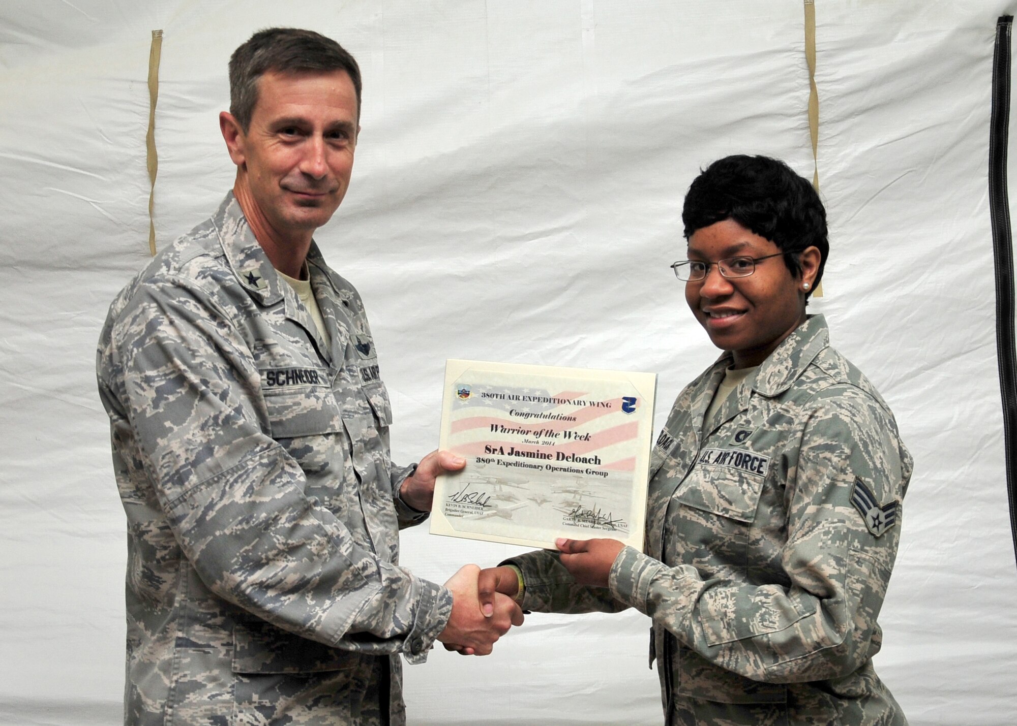 Air Force Brig. Gen. Kevin Schneider, 380th Air Expeditionary Wing commander, presents Air Force Senior Airman Jasmine Deloach, 727th Expeditionary Air Control Squadron electronic protection technician, a warrior of the week certificate at an undisclosed location in Southwest Asia, March 19, 2014. Deloach is a native of Statesboro Ga., and is deployed from Hunter Army Airfield. (U.S. Air Force photo by Staff. Sgt. Michael Means)
