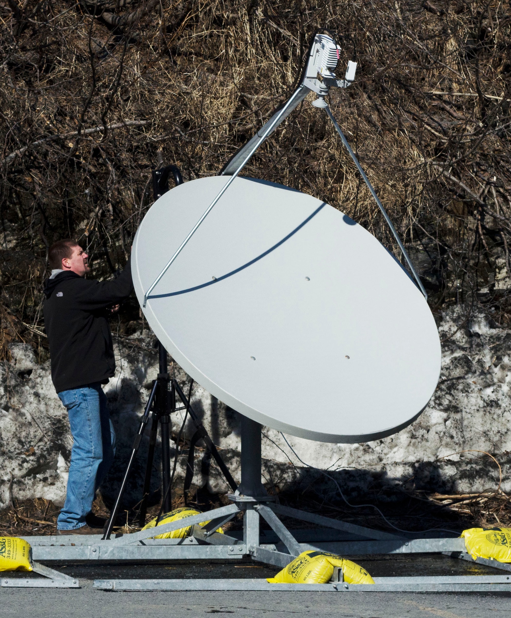 Jason Kelly, a systems technician with Bering Straits Information Technologies, works on a satellite while setting up the Alaska Land Mobile Radio Transportable during Alaska Shield 14, March 28, 2014. Alaska Shield 14 is an exercise that involves state, federal, military, and local agencies, designed to test the response and coordination of the a disaster modeled after the 1964 earthquake and subsequent tsunami that devastated much of South Central Alaska including the city of Valdez. (U.S. Army photo by Spc. True Thao)