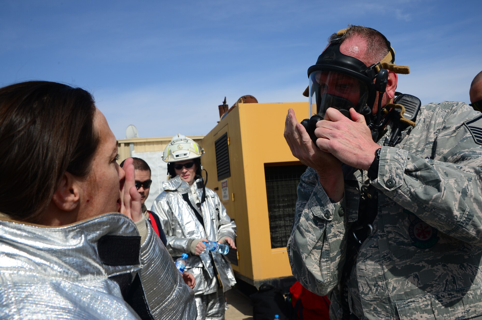 Master Sgt. Micheal Chisholm, 386th Expeditionary Civil Engineer Squadron assistant fire chief, briefs Lt. Col. Carol Miller, the 386th Expeditionary Mission Support Group deputy commander, on proper wear of a firefighter gas mask during a burn trainer event at an undisclosed location in Southwest Asia. The event allowed senior leaders to gain a better understanding for firefighter duties while deployed to The Rock. (U.S. Air Force photo by Senior Airman Desiree W. Moye)
