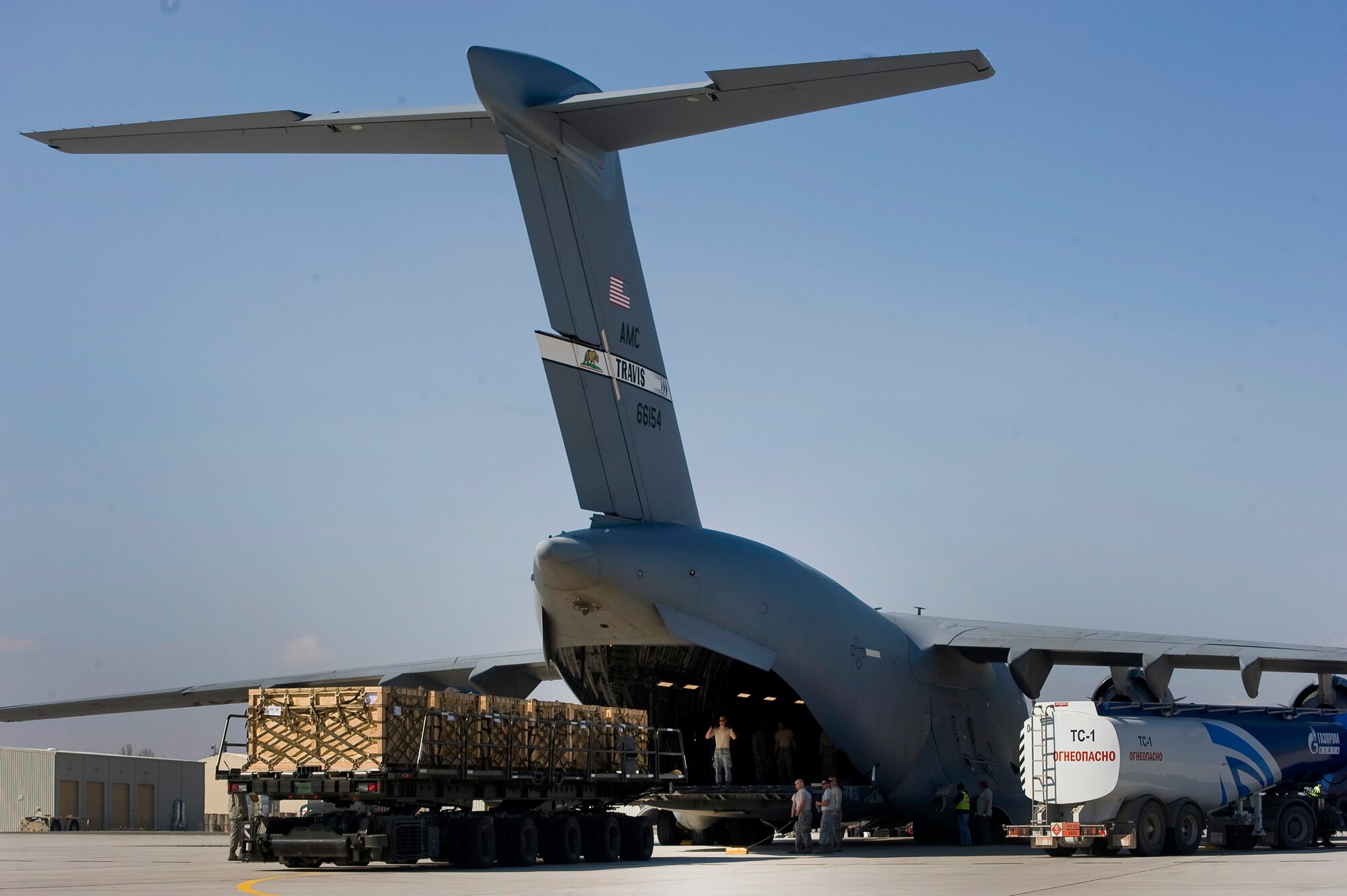 A 376th Expeditionary Logistics Readiness Squadron Airman guides cargo onto a C-17 Globemaster III while a fuel truck gasses the aircraft at Transit Center at Manas, Krygyzstan, March 28, 2014.  This picture is becoming commonplace as tons of cargo requires shipment before the facility closes.  The Kyrgyz parliament voted for the center lease to end on July 11, 2014. (U.S. Air Force photo/Lt Col Max Despain)