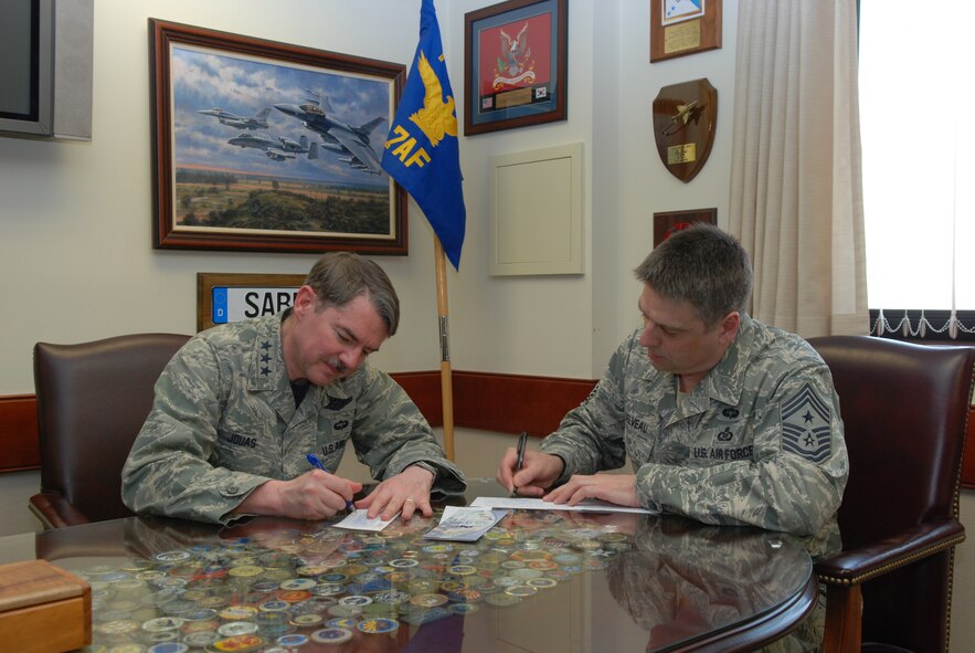 OSAN AIR BASE, Republic of Korea - Lt. Gen. Jan-Marc Jouas, 7th Air Force commander, and Command Chief Master Sgt. Scott Delveau, 7th AF Command Chief, sign their Air Force Assistance Fund pledges in General Jouas's office March 28, 2014. Osan AB has three AFAF goals this year: attain 100 percent contact, beat last year's participation rate by five percent and raise $105,000 to care for Airmen and their families. The AFAF campaign runs through May 12. For more information, see your unit's AFAF representative. (U.S. Air Force photo by Tech. Sgt. Thomas J. Doscher)