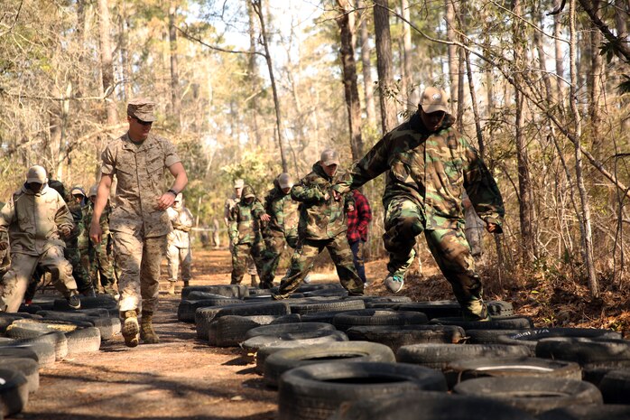 Dreher High School Navy Junior Reserve Officer Training Corps cadets run through tires, while wearing Mission Oriented Protective Posture (MOPP) suits during a period of instruction from chemical, biological, radiological and nuclear defense specialists with CBRN Platoon, Combat Logistics Regiment 27, 2nd Marine Logistics Group aboard Camp Lejeune, N.C., March 27, 2014.. The CBRN training also introduced the cadets to some of the Marine Corps’ decontamination procedures to minimize the threat of attacks. (U.S. Marine Corps photo by Lance Cpl. Shawn Valosin)