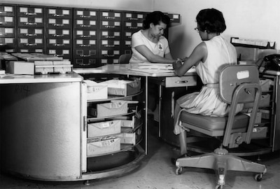 Image result for images of “Two clerks at work on aerial film control files in the DIA Cafritz Building, 1960s