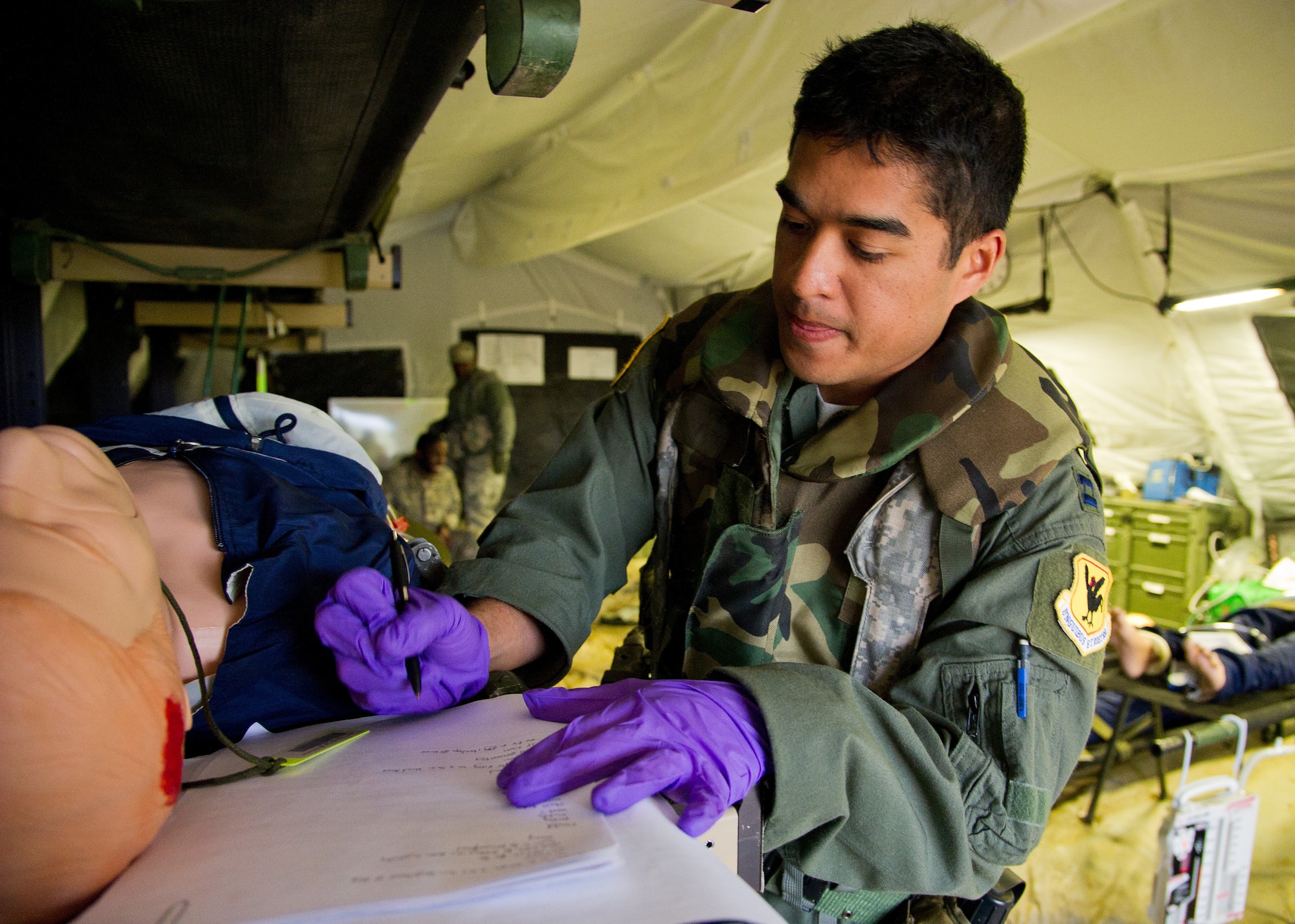 U.S. Air Force Capt. Ray Mamuad, clinical nurse, from the 18th Aeromedical Evacuation Squadron, Kadena Air Base, Okinawa, Japan, documents a simulated patients medical condition and treatment during a field exercise at the Joint Readiness Training Center (JRTC), Fort Polk, La., March 16, 2014. Service members at JRTC 14-05 are educated in combat patient care and aeromedical evacuation in a simulated combat environment. (U.S. Air Force photo by Staff Sgt. Joseph Araiza) 

