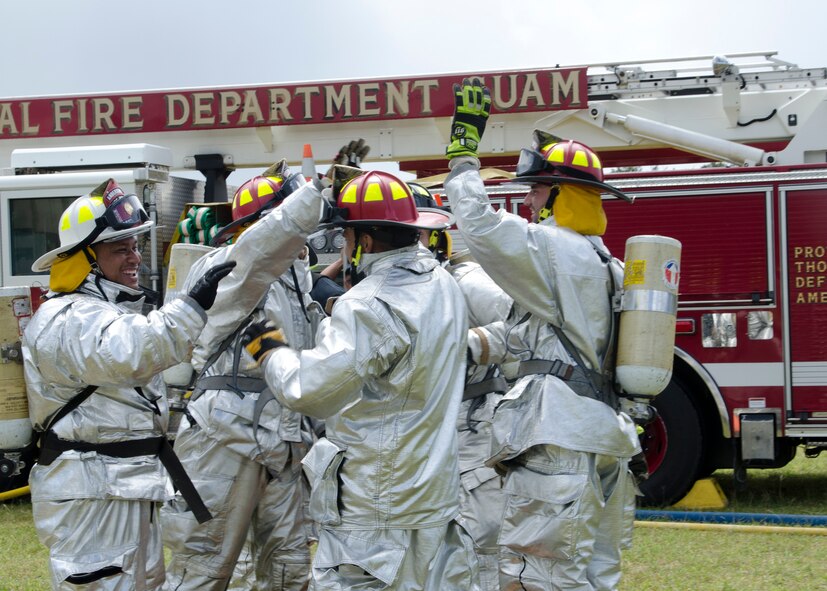 36th Civil Engineer Squadron Fire and Emergency Services firefighters celebrate after completing a team obstacle course during the 2014 Guam Firefighter Muster Challenge March 15, 2014, in Tamuning, Guam. Team Andersen placed first overall in the two-day competition. (U.S. Air Force photo by Senior Airman Katrina M. Brisbin/Released)