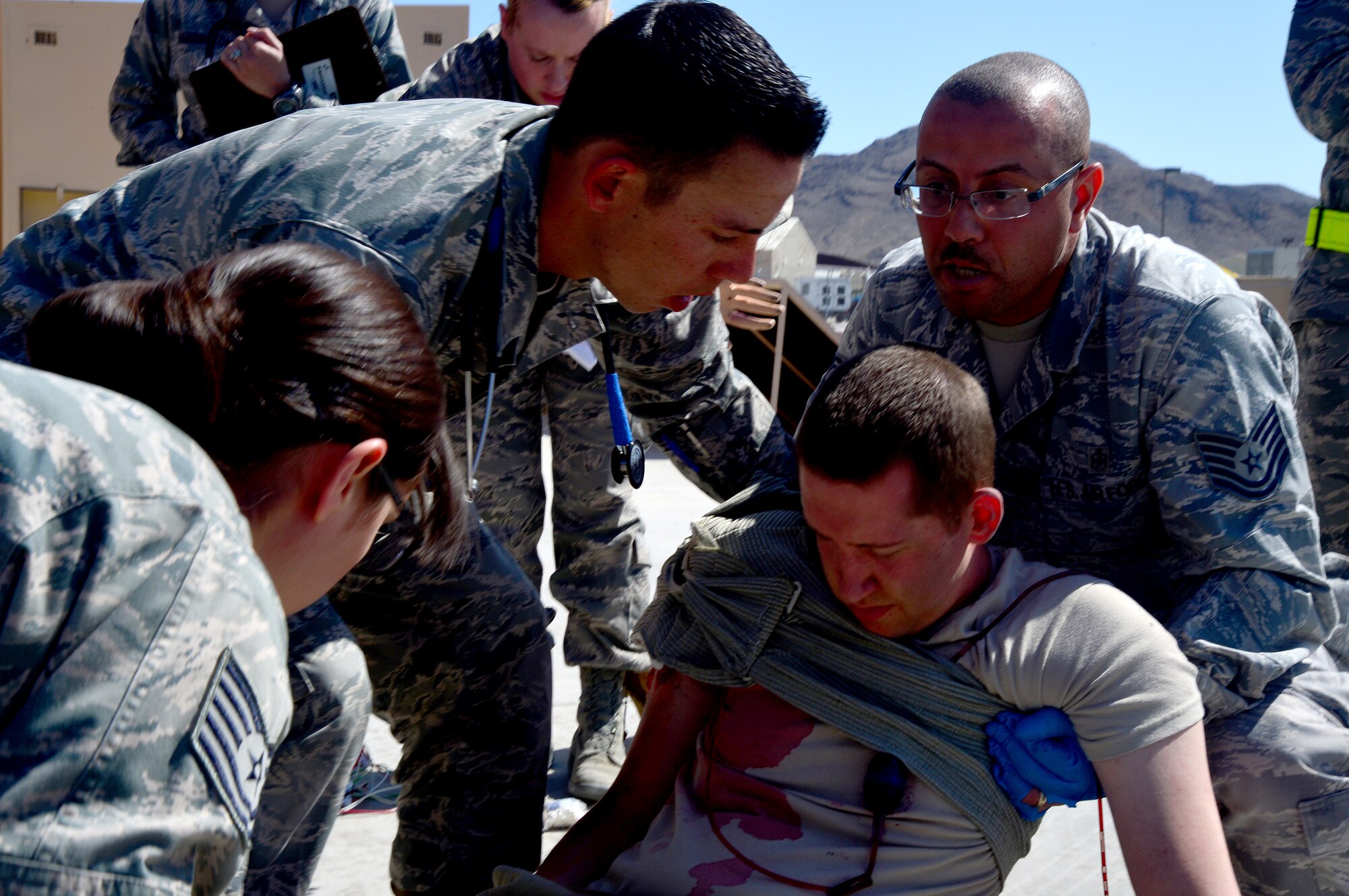 Airmen from various units lift a simulated wounded Airman during an active shooter exercise at Creech Air Force Base, Nev., March 25, 2014. The exercise with Nellis Air Force Base, Nev., tested the command and control communications between bases to better prepare for future incidents. Moulage is applied to Airmen acting as victims before the exercise begins to provide an element of realism, allow accurate evaluation of medical personnel, and provide realistic training opportunities. (U.S. Air Force photo by Staff Sgt. N.B./Released)
