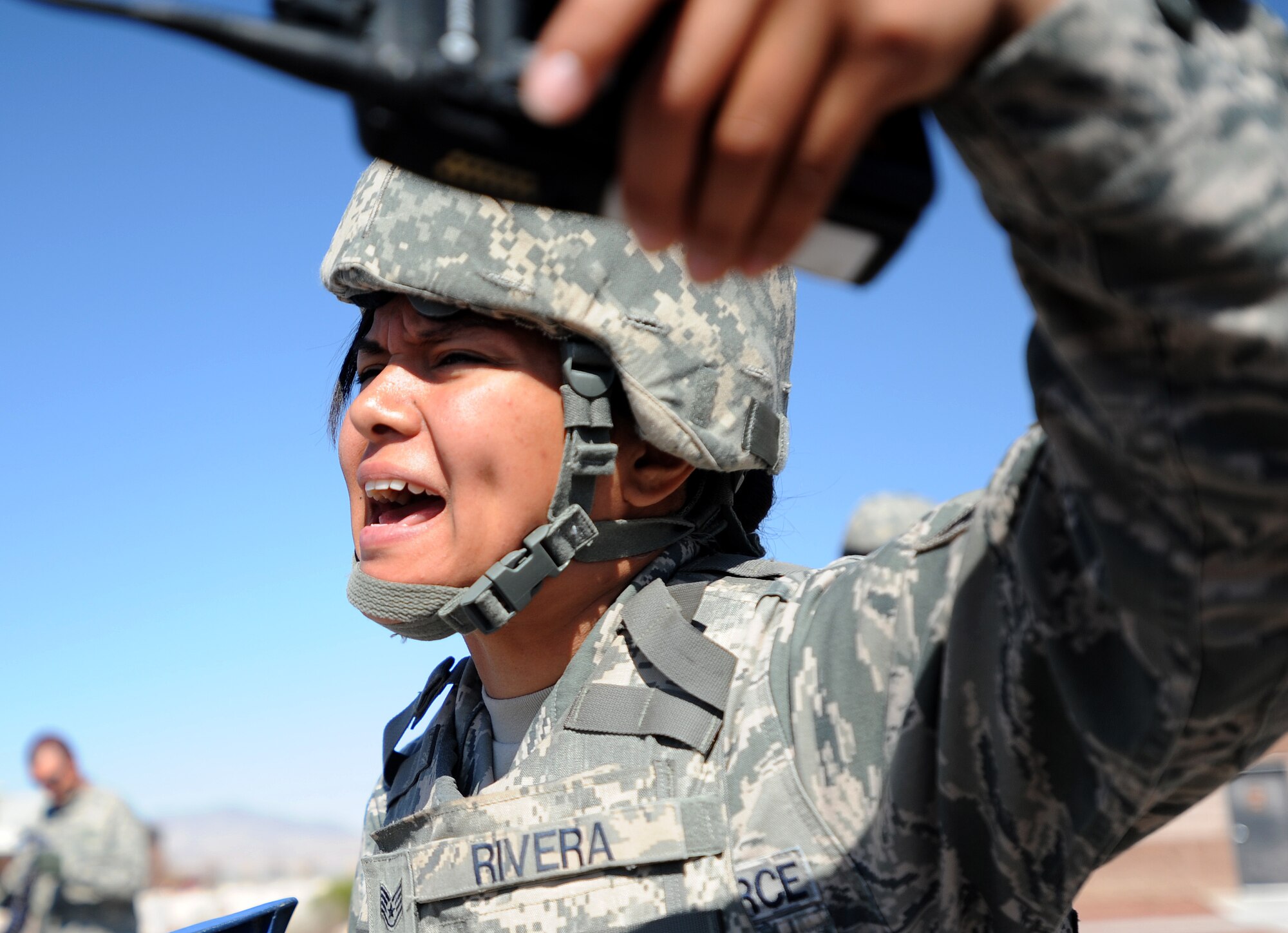 Staff Sgt. Liza Rivera, 799th Security Forces Squadron patrolman, yells to first responders during a simulated active shooter exercise at Creech Air Force Base, Nev., March 25, 2014. The scenario between Creech and Nellis Air Force Bases tested the emergency response capabilities of installation personnel, first responders and critical notification infrastructure. (U.S. Air Force photo by Senior Master Sgt. C.R./Released)