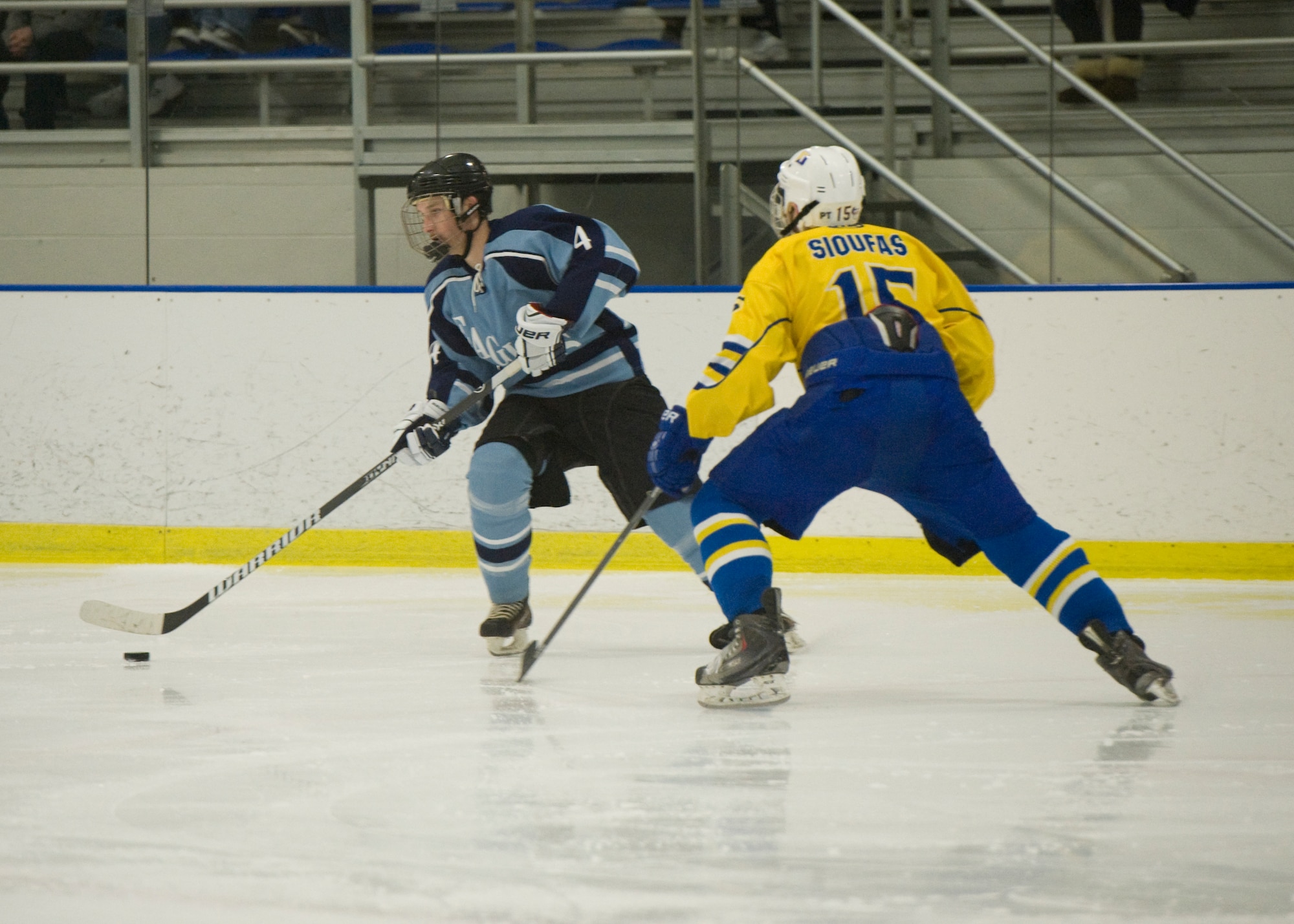 Kyle Gaylord, Dover Eagles defenseman, carries the puck past Nick Sioufas, Blue Hens defenseman, during a charity hockey game March 23, 2014, at the Fred Rust Ice Arena on the University of Delaware campus in Newark, Del. The Blue Hens won the game 16-5. (U.S. Air Force photo/Airman 1st Class Zachary Cacicia)