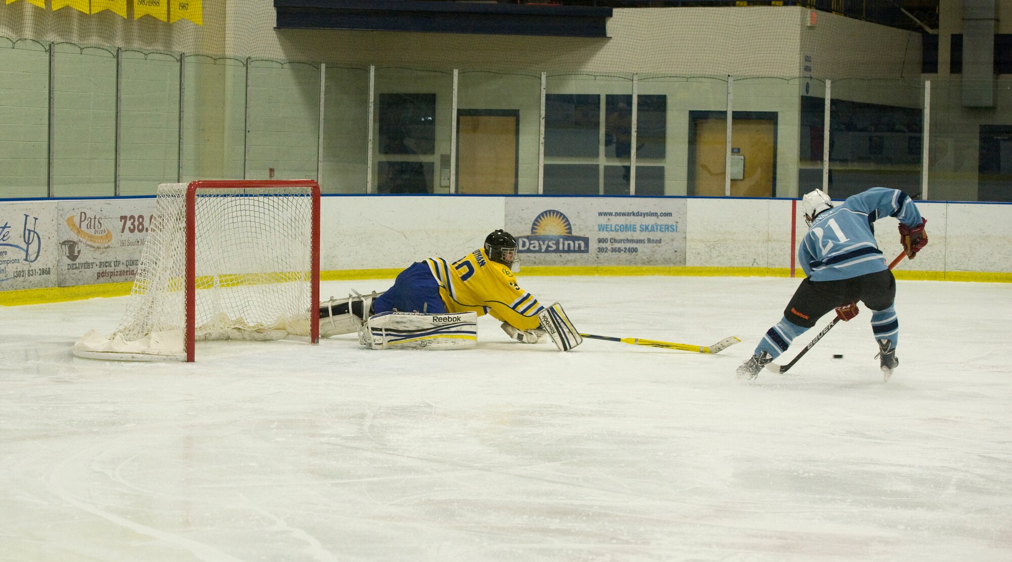 Lewis Brotman, Blue Hens goalie, poke checks Sam Ernst, Dover Eagles center, during a charity hockey game March 23, 2014, at the Fred Rust Ice Arena on the University of Delaware campus in Newark, Del. The Blue Hens goalies managed to hold the Eagles to five goals. (U.S. Air Force photo/Airman 1st Class Zachary Cacicia)