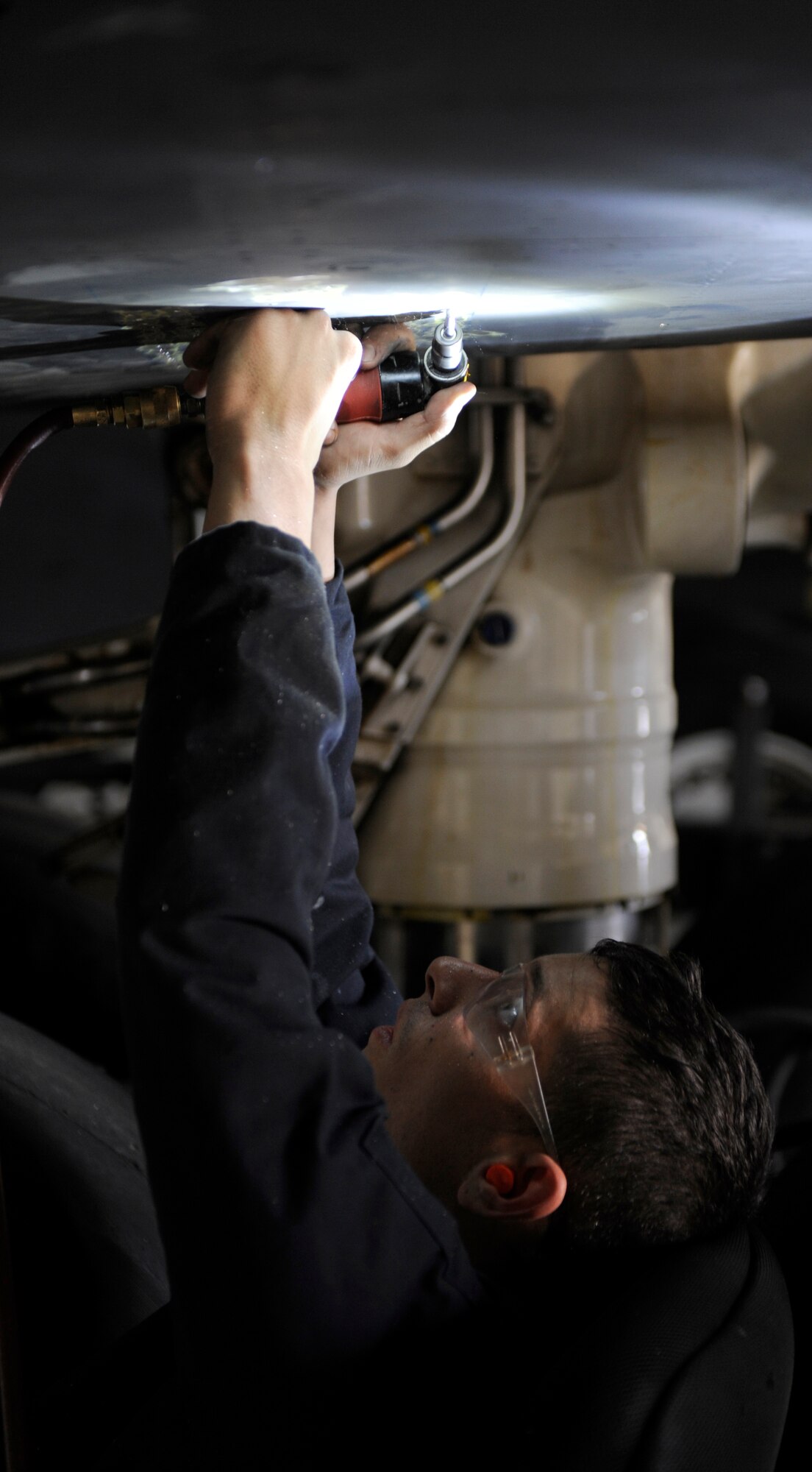 U.S. Air Force Staff Sgt. Cory Hoefling, 7th Equipment Maintenance Squadron, repairs cracks on a lower panel of a B-1B Lancer March 27, 2014, at Dyess Air Force Base, Texas. The damages are repaired by drilling a hole on each end of the crack to stop it from spreading and then placing a temporary panel over the entire damaged area. (U.S. Air Force photo by Airman 1st Class Alexander Guerrero/Released)