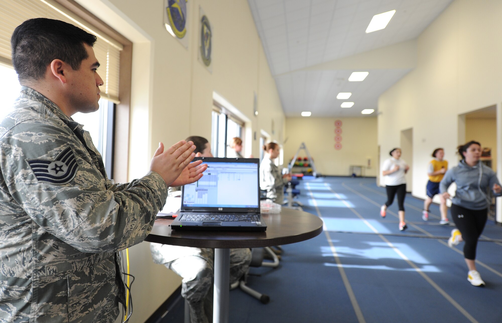 Staff Sgt. Juan Hernandez cheers on physical fitness test takers at Fairchild Air Force Base, Wash., March 27, 2014. Hernandez is from the 92nd Force Support Squadron. Pacers are allowed to help test takers during the mile an a half timed run. (U.S. Air Force photo by Airman 1st Class Janelle Patiño/Released)