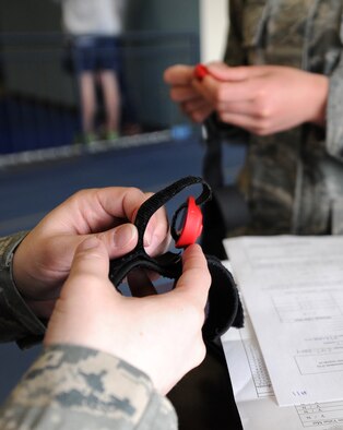 Staff Sgt. Lindsey Griffin sets up the lap counting device for the mile and a half run during the physical fitness test at Fairchild Air Force Base, Wash., March 27, 2014. Griffin is from the 92nd Security Forces Squadron. The device counts the laps and records the runner's time. (U.S. Air Force photo by Airman 1st Class Janelle Patiño/Released)
