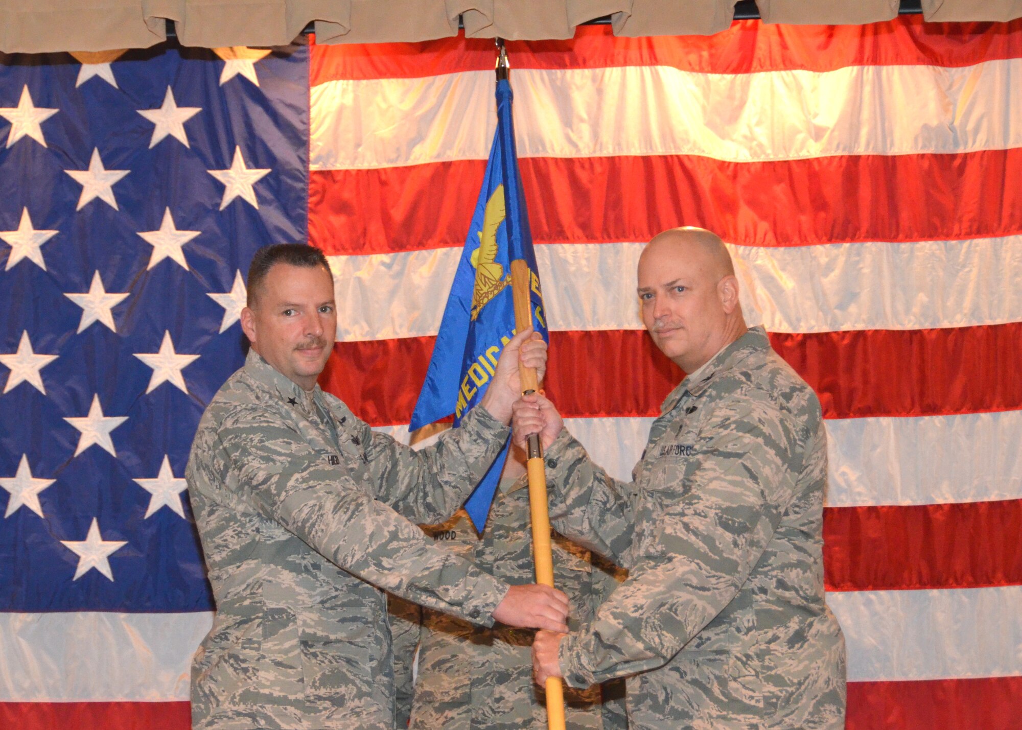 New 81st Medical Group and Keesler Medical Center commander Col. (Dr.) Thomas Harrell, right, accepts the unit guidon from Brig. Gen. Patrick Higby, 81st Training Wing commander, during the March 28 change of command ceremony held in  the medical center’s Don Wylie Auditorium.  The new commander comes to Keesler Air Force Base from Joint Base Elmendorf-Richardson, Alaska, where he commanded the Department of Defense/Veterans Affairs Joint Venture Hospital and also served as the Alaskan Command command surgeon.  Former commander Brig. Gen. (Dr.) Kory Cornum has been reassigned to Scott AFB, Ill., as Air Mobility Command command surgeon.