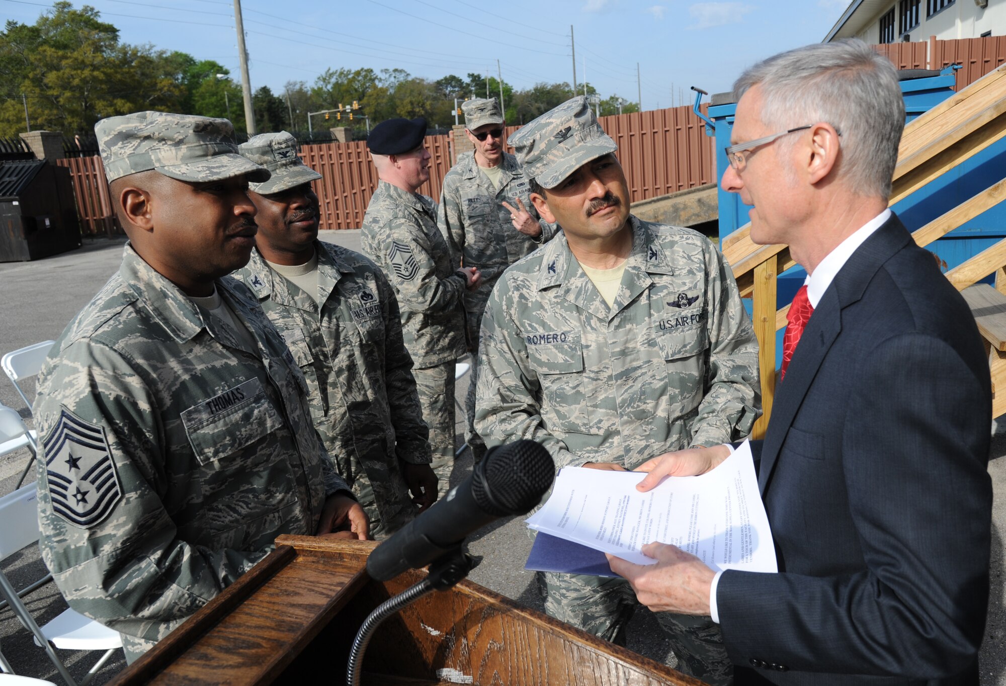 Chief Master Sgt. Farrell Thomas, 81st Training Wing command chief, Col. Mark Vivians, 81st Mission Support Group commander, and Col. René Romero, 81st TRW vice commander, listen to Jeffrey Hawting, L.C. Industries chief operating officer, speak about how the blind are employed at L.C. Industries during the Ability One Base Supply Center ribbon cutting ceremony March 27, 2014, at Keesler Air Force Base, Miss.  Supply vending tables were on display for the event. (U.S. Air Force photo by Kemberly Groue)