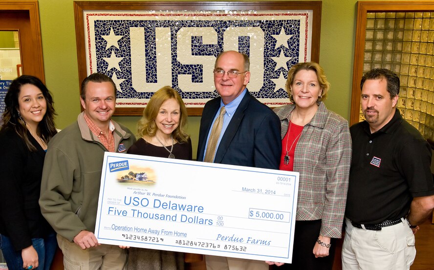 Mitzi Perdue, Arthur W. Perdue Foundation board of directors member, third from the left, presents a $5,000 check to the United Services Organization Delaware March 31, 2014, at the USO lounge on Dover Air Force Base, Del. Accepting the check on behalf of the USO Delaware are, left to right: Yolanda Bottorf, Families of the Fallen support manager for the USO; Bruce Kmiec, USO Delaware operations manager; David McClellan, 512th Maintenance Group honorary commander; Mary Johnson, USO Delaware Advisory Council member; and Bill Flanders, USO Delaware program coordinator. The donation will be used to support programs and services for service men, women and their families. (U.S.  Air Force photo/Roland Balik)