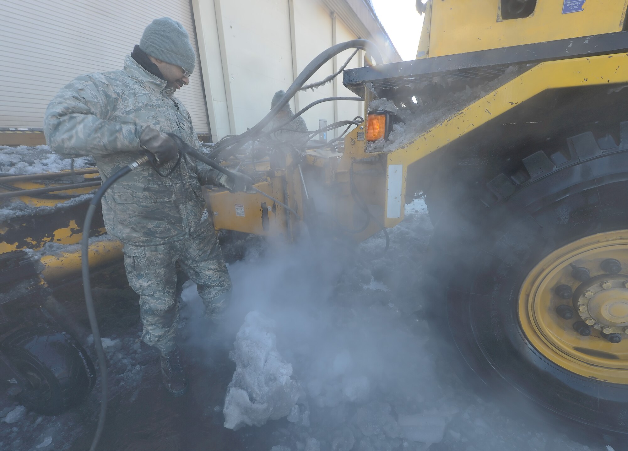 Airman 1st Class Ernest Gilmore, 436th Civil Engineer Squadron, pressure washes a piece of snow removal equipment using heated water on March 20, 2014, at Dover Air Force Base, Del. Gilmore is a heating and air conditioning technician by trade but has been pulled to assist with a group equipment clean-up in an effort to quickly return the equipment to service. (U.S. Air Force photo/Greg L. Davis)