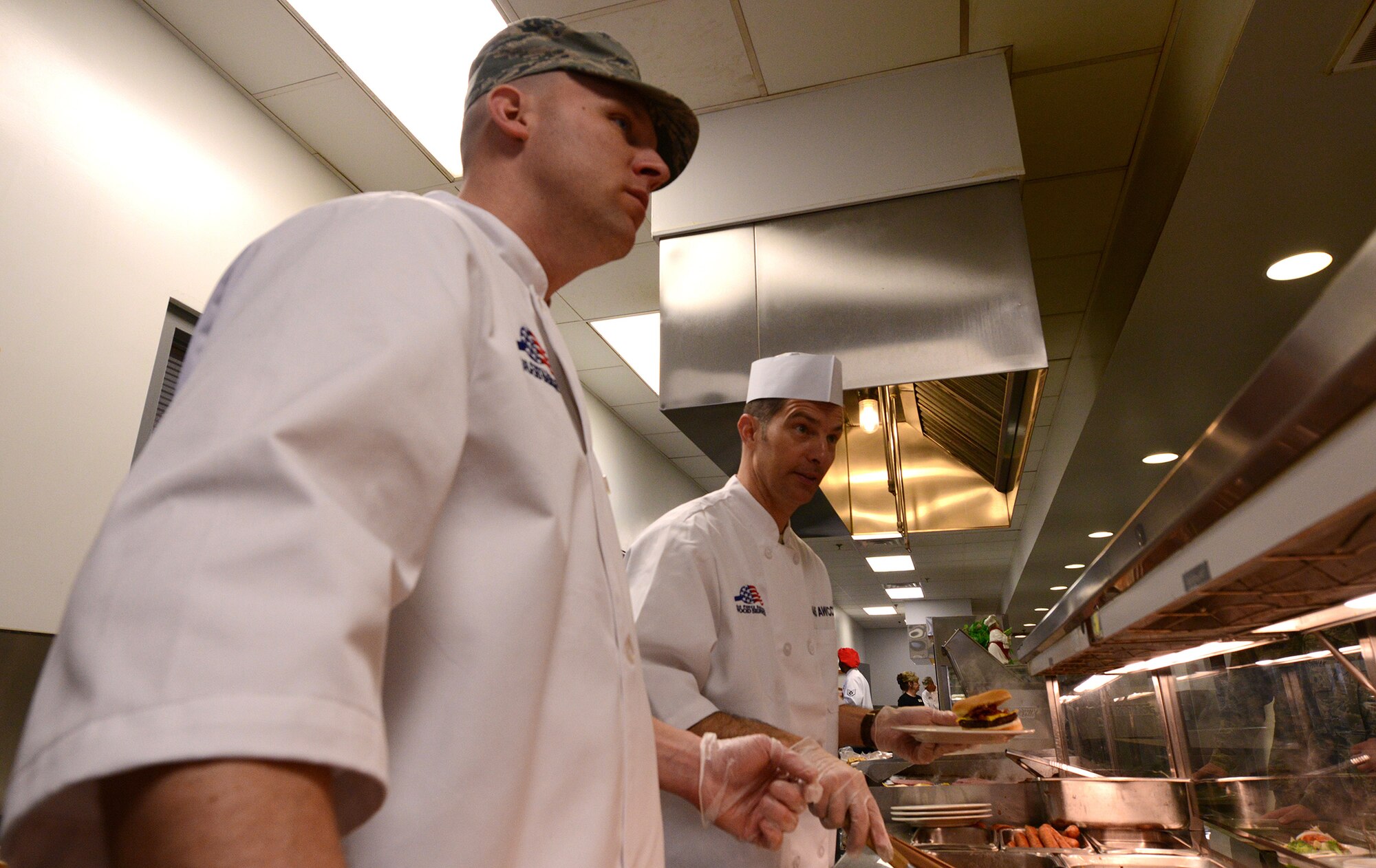WRIGHT-PATTERSON AIR FORCE BASE, Ohio - Maj. Kent Shea, 445th Force Support Squadron commander, left, and Lt. Col. Mike Brandenburg, 445th Mission Support Group deputy commander, serve Airmen during the March 8, 2014 lunch hour at the Pitsenbarger Dining Facility here. The commanders were taking part in the “Serve It Up Initiative.” The project helps boost morale and give the commanders and first sergeants a chance to sport their new chef's coats too. The initiative will go on indefinitely and the coats will be inherited by future commanders when they join the unit. (U.S. Air Force photo/Tech. Sgt. Frank Oliver)