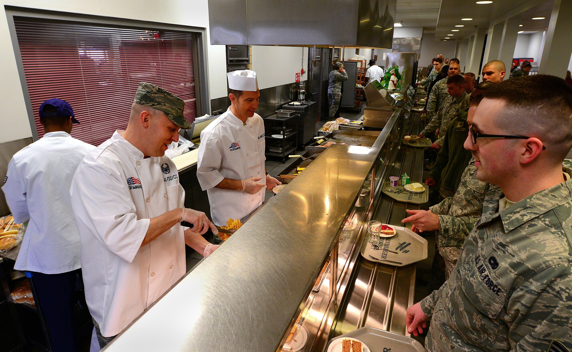 WRIGHT-PATTERSON AIR FORCE BASE, Ohio - Maj. Kent Shea, 445th Force Support Squadron commander, left, and Lt. Col. Mike Brandenburg, 445th Mission Support Group deputy commander, serve Airmen during the March 8, 2014 lunch hour at the Pitsenbarger Dining Facility here. The commanders were taking part in the “Serve It Up Initiative.” The project helps boost morale and give the commanders and first sergeants a chance to sport their new chef's coats too. The initiative will go on indefinitely and the coats will be inherited by future commanders when they join the unit. (U.S. Air Force photo/Tech. Sgt. Frank Oliver)
