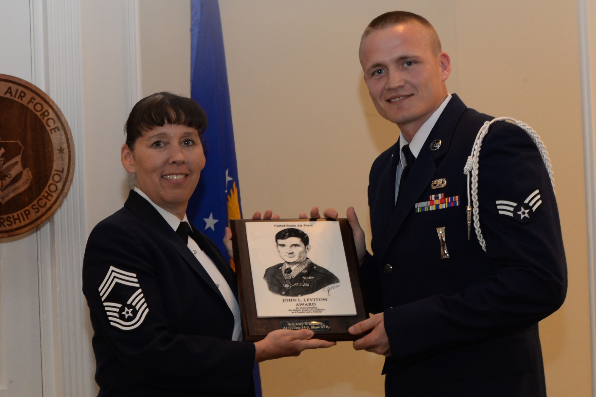 U.S. Air Force Senior Airman Jerry Madaris, 20th Maintenance Group, receives the John Levitow award from Chief Master Sgt. Suzanne Talbert, 20th Mission Support Group superintendent, Shaw Air Force Base, S.C., March 27, 2014. The John Levitow Award is given to the person with the highest average of instructor and student points, and it is the highest award in enlisted professional military education. (Air Force photo by Airman 1st Class Michael A. Cossaboom/Released)