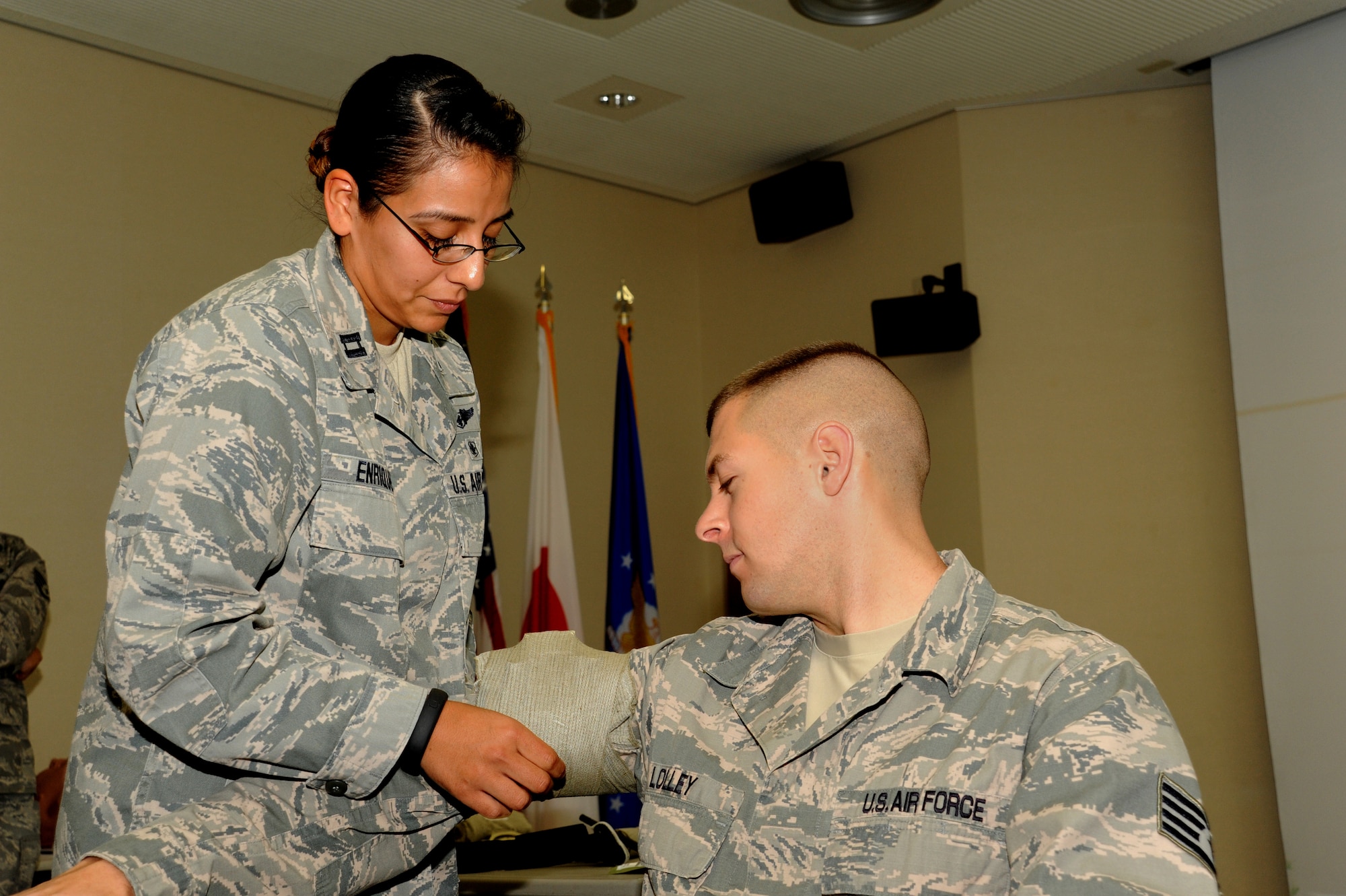 U.S. Air Force Capt. Christina Enriquez, 18th Air Expeditionary Squadron flight nurse, demonstrates how to perform an upper-arm wrap on Staff Sgt. Dennis Lolley, 2nd Reconnaissance Squadron transportation management office trainer, during a self-aid and buddy care class on Kadena Air Base, Japan, March 27, 2014. As part of the hands-on SABC training, Airmen go over the contents of an Individual First Aid Kit. SABC focuses on how to use the items from the kit to help individuals get a medical emergency under control until help arrives. (U.S. Air Force photo by Airman 1st Class Zackary A. Henry)