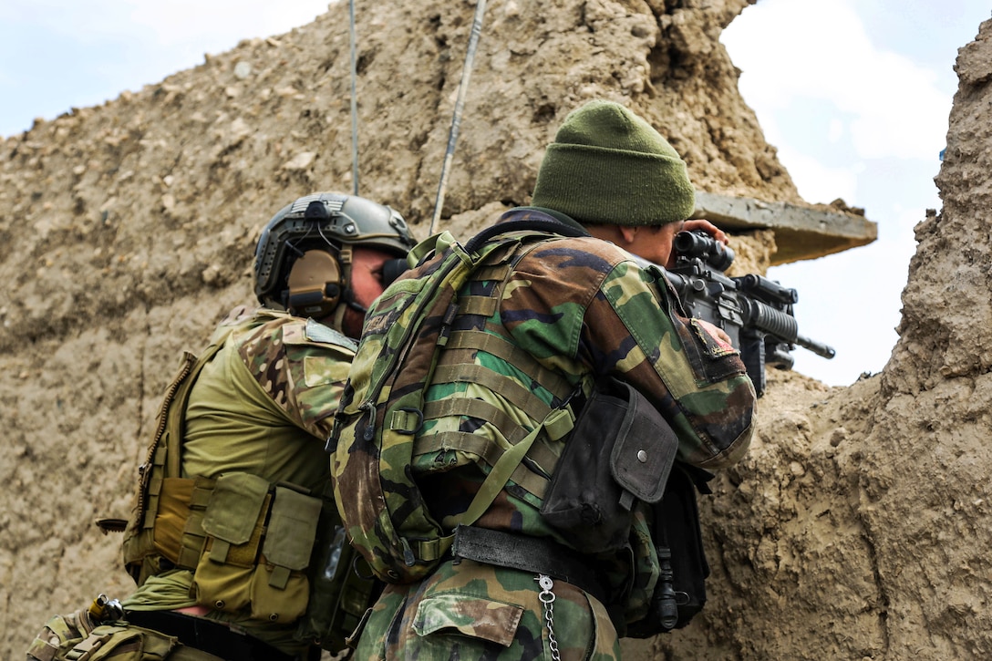 A U.S. Special Forces soldier, left, and an Afghan army commando scan the area for enemy activity after taking fire during a clearing operation in the Khogyani district of Afghanistan's Nangarhar province, March 20, 2014. The soldier is assigned to Combined Joint Special Operations Task Force-Afghanistan, and the Afghan commando is assigned to the 6th Special Operations Kandak. The commandos, advised and assisted by U.S. Special Forces soldiers, conducted the operation to disrupt insurgent activity in the area.