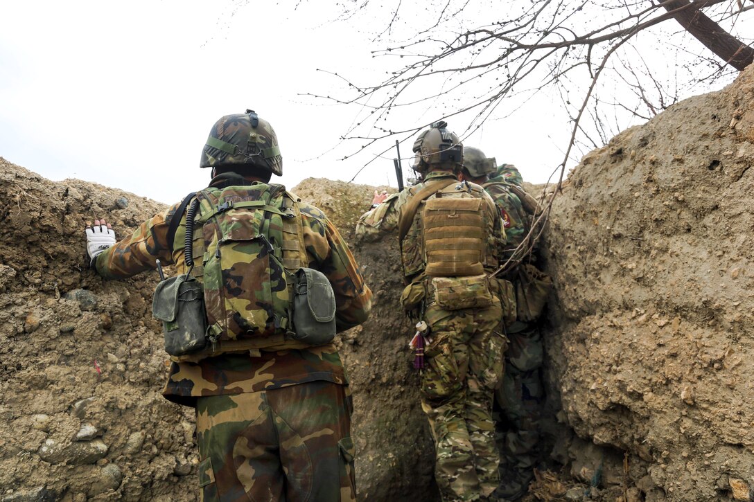 A U.S. Army Special Forces soldier, center, and Afghan army commandos observe as a squad of commandos clear a compound in the Khogyani district of Afghanistan's Nangarhar province, March 20, 2014.