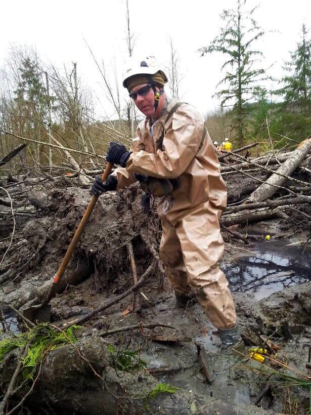 A Air National Guardsman wades through mud and debris to search for survivors in Oso, Wash., March 27, 2014, following a deadly mudslide.